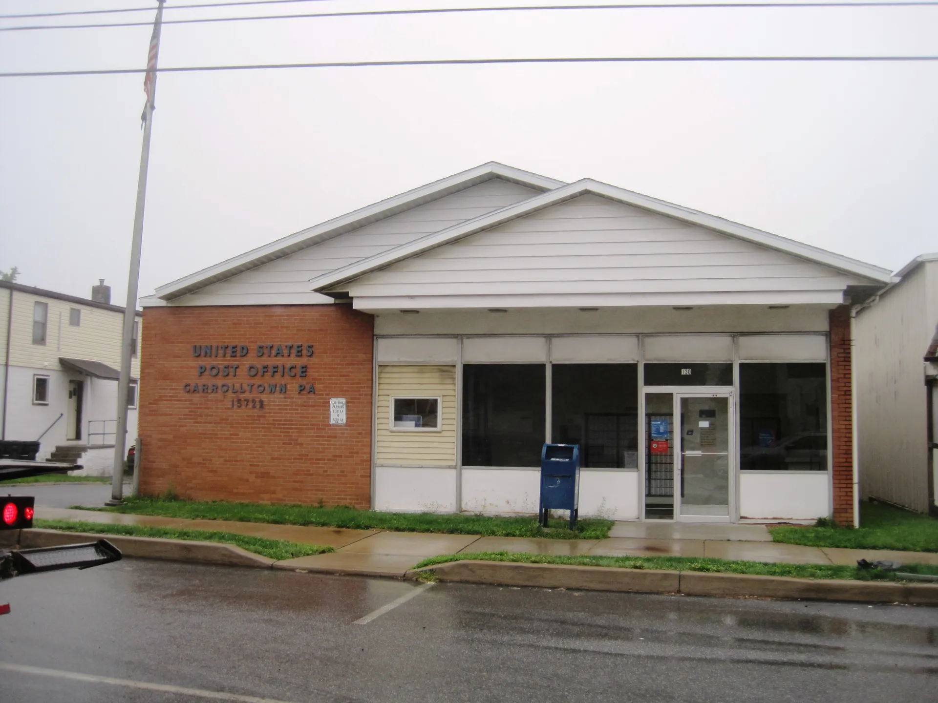 Carrolltown's post office is a white-sided building with a brick front and a blue mailbox, viewed from U.S. Route 219.