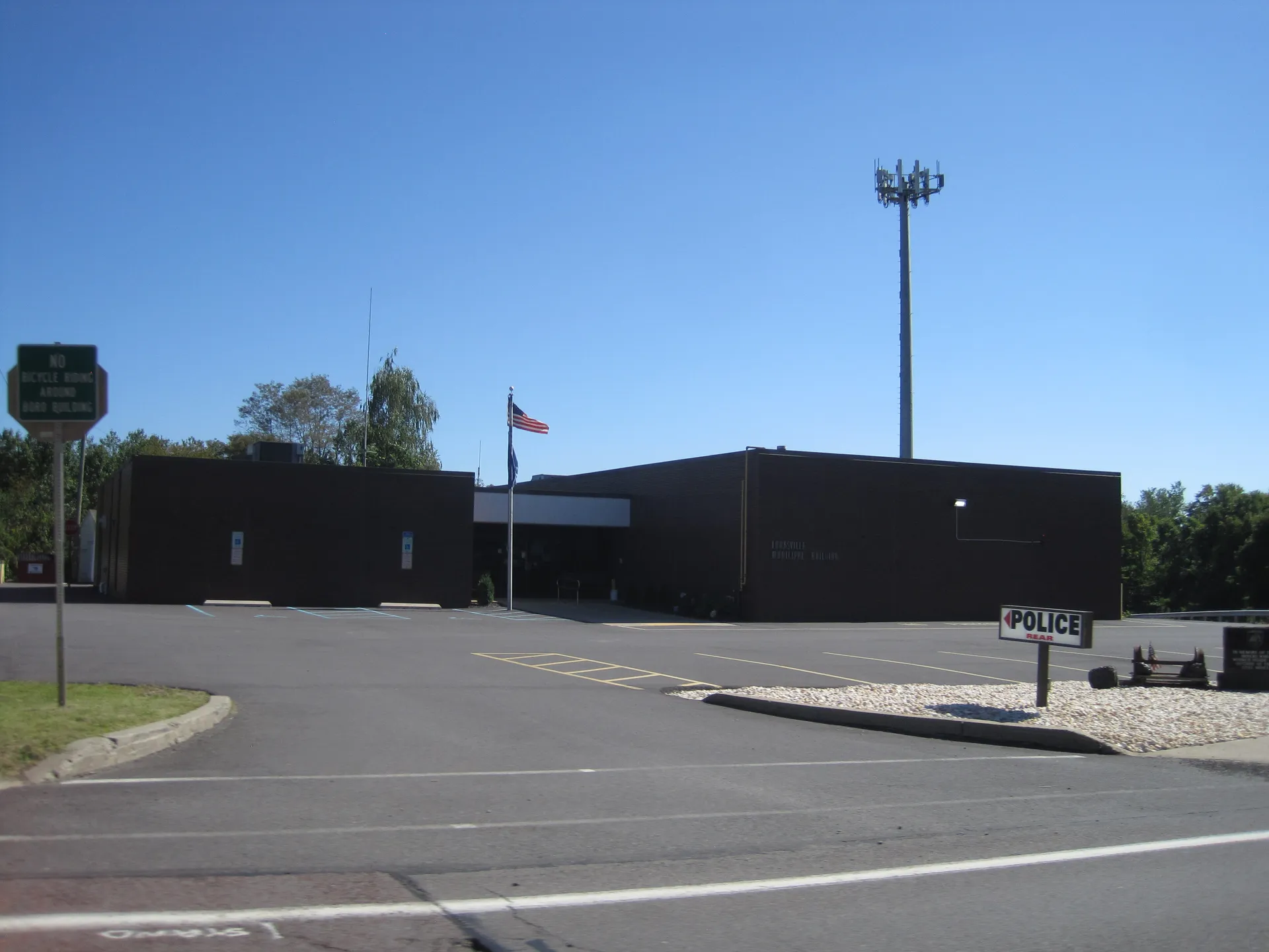 Larksville's municipal building is a dark brick structure with a flagpole and a tall light tower beside its lot.