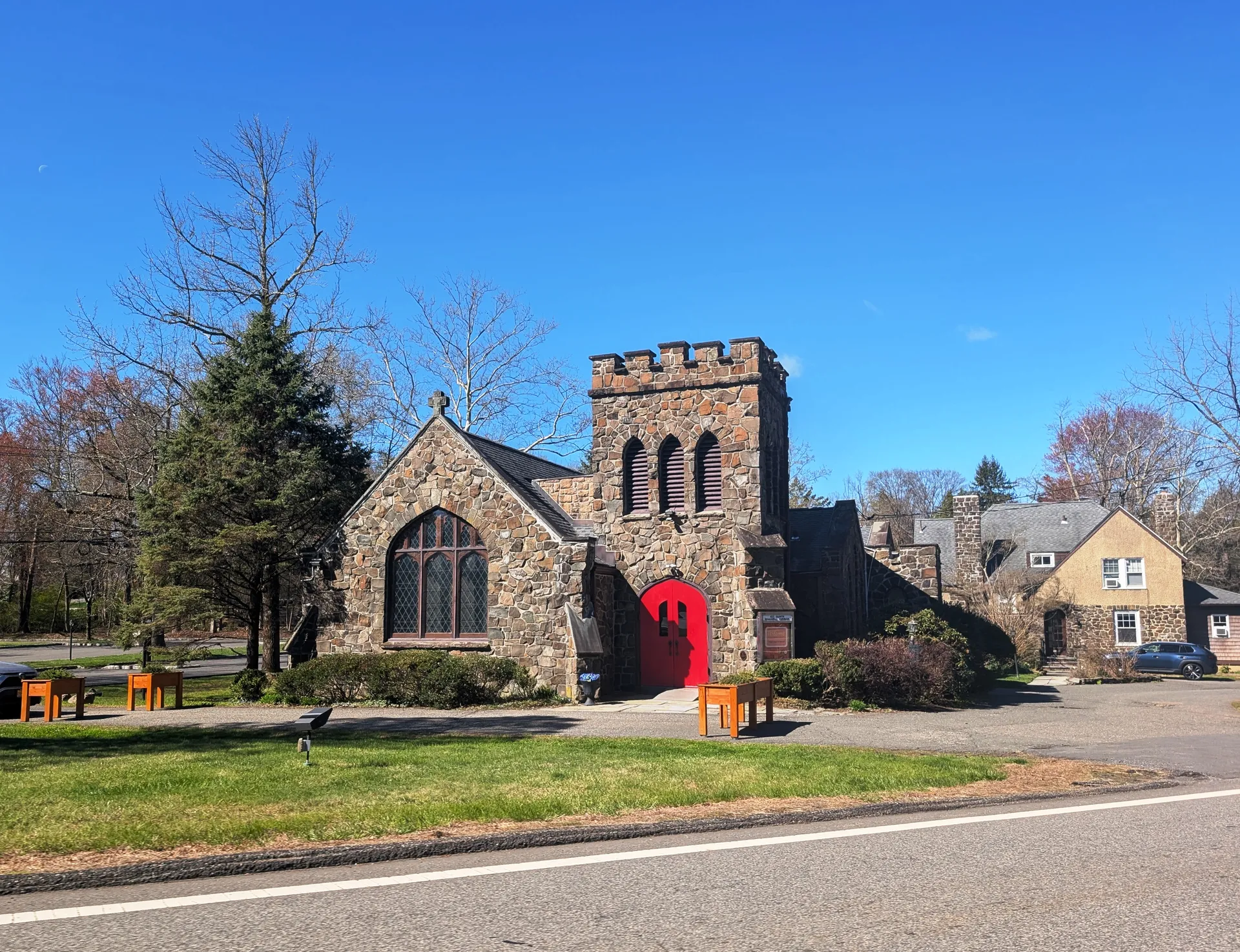 All Saints Episcopal Church in Millington is a stone church with a square tower and a bright red door.