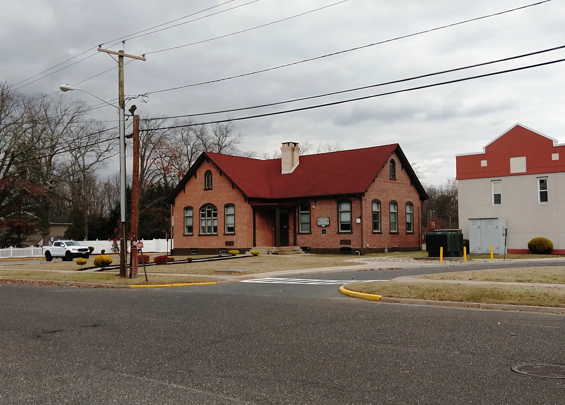 The Busch Building in Hainesport is a small red brick building with a red roof and arched windows by the roadside.