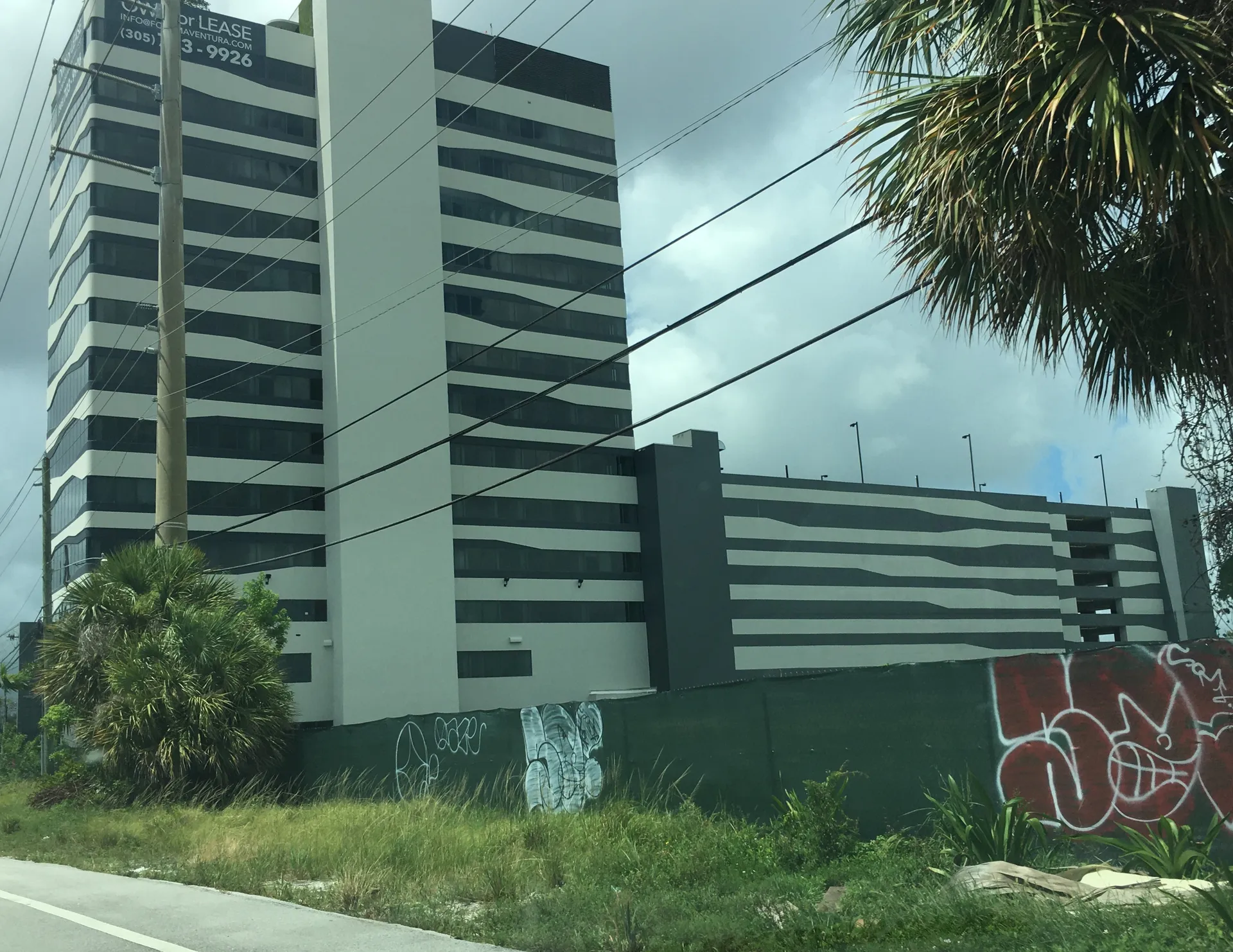 The site of the Aventura station (fenced empty lot in foreground) along Dixie Highway in Ojus, Florida on 24 July 2020. FORUM Aventura is the building in the background.