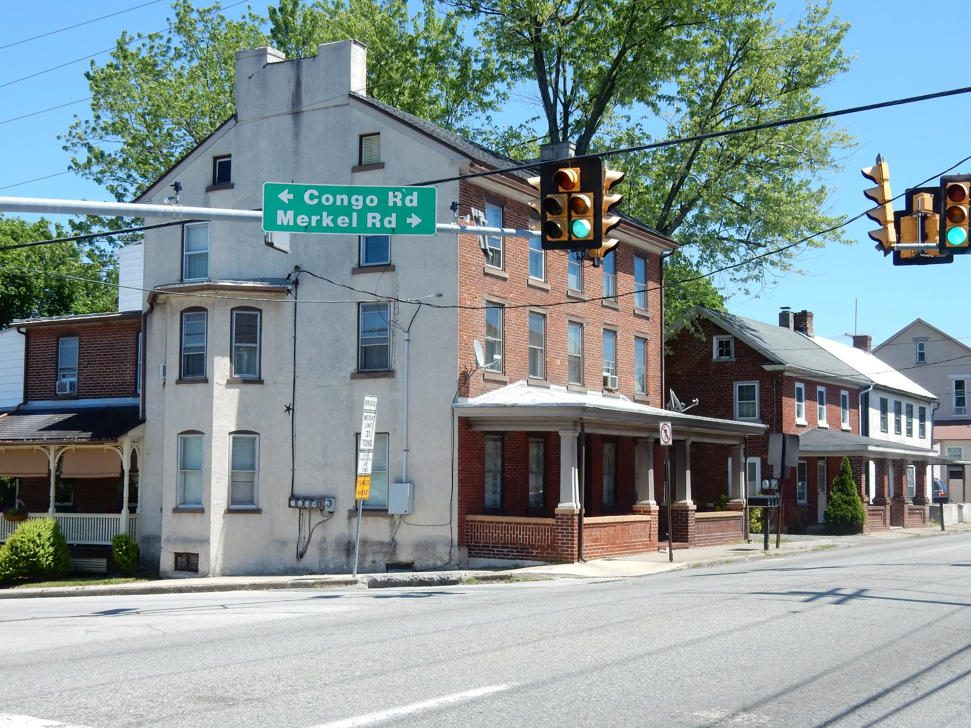 East Philadelphia Avenue meets Merkel Road in Gilbertsville beside a three-story brick building with a green street sign.