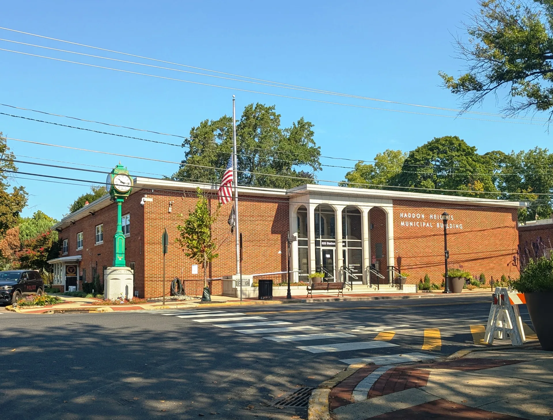 The Haddon Heights Municipal Building is a red brick structure with a white arched portico, a flag and a lamppost out front.