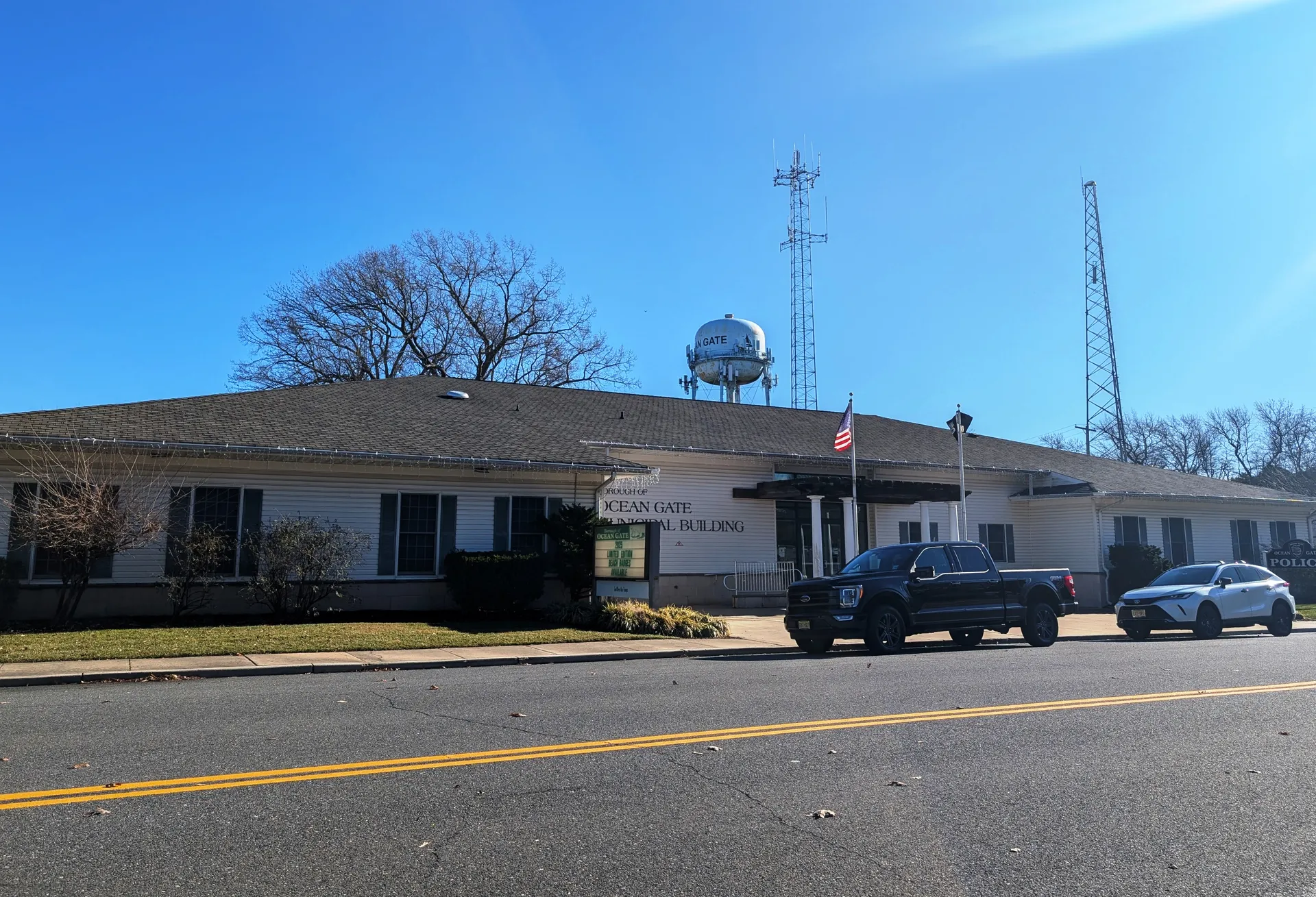 The Ocean Gate municipal building is a low tan building with a water tower rising behind it.