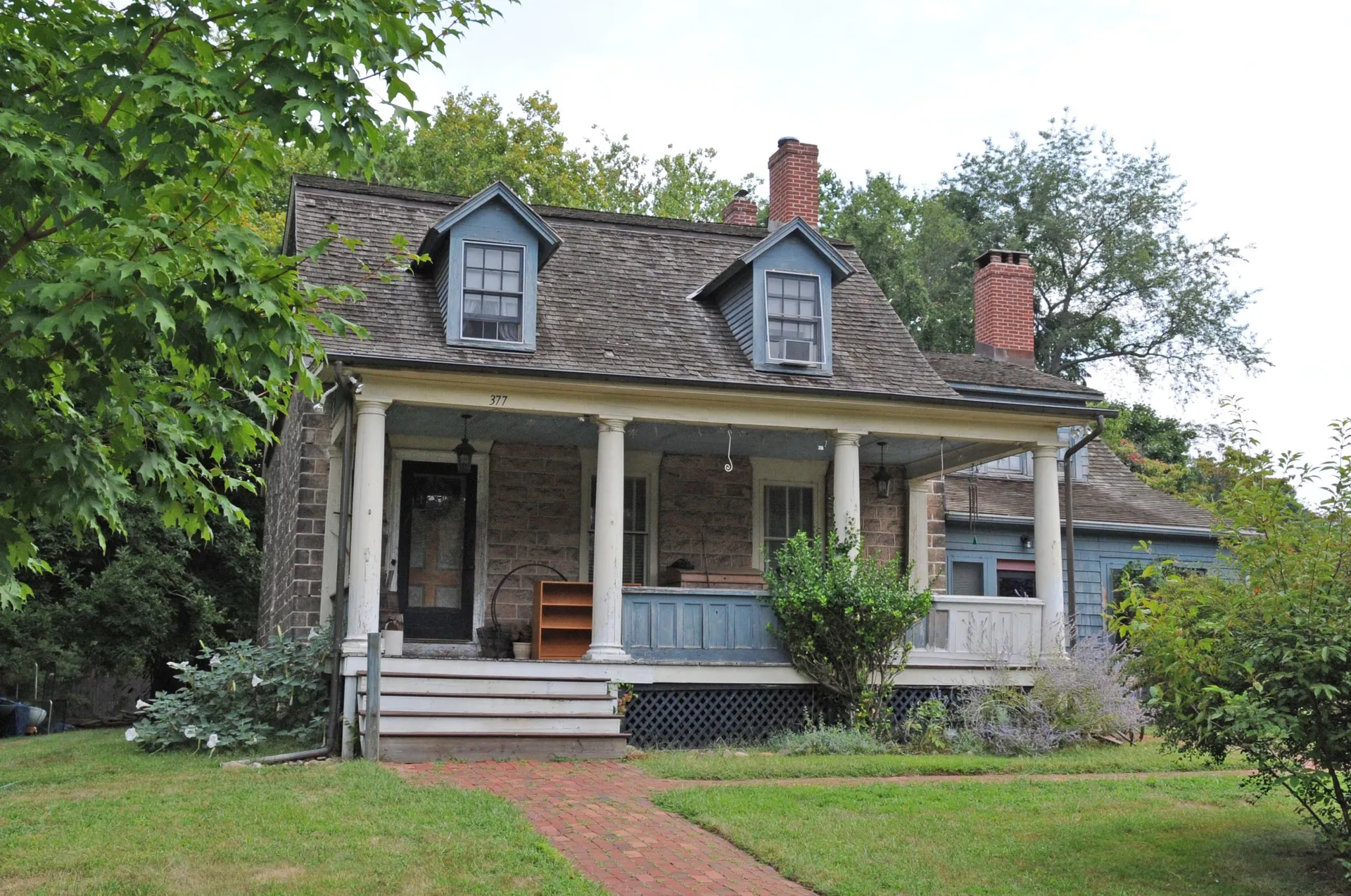 The Haring-Auryanson House in Closter is a stone cottage with dormers, a white columned front porch and a brick walkway.