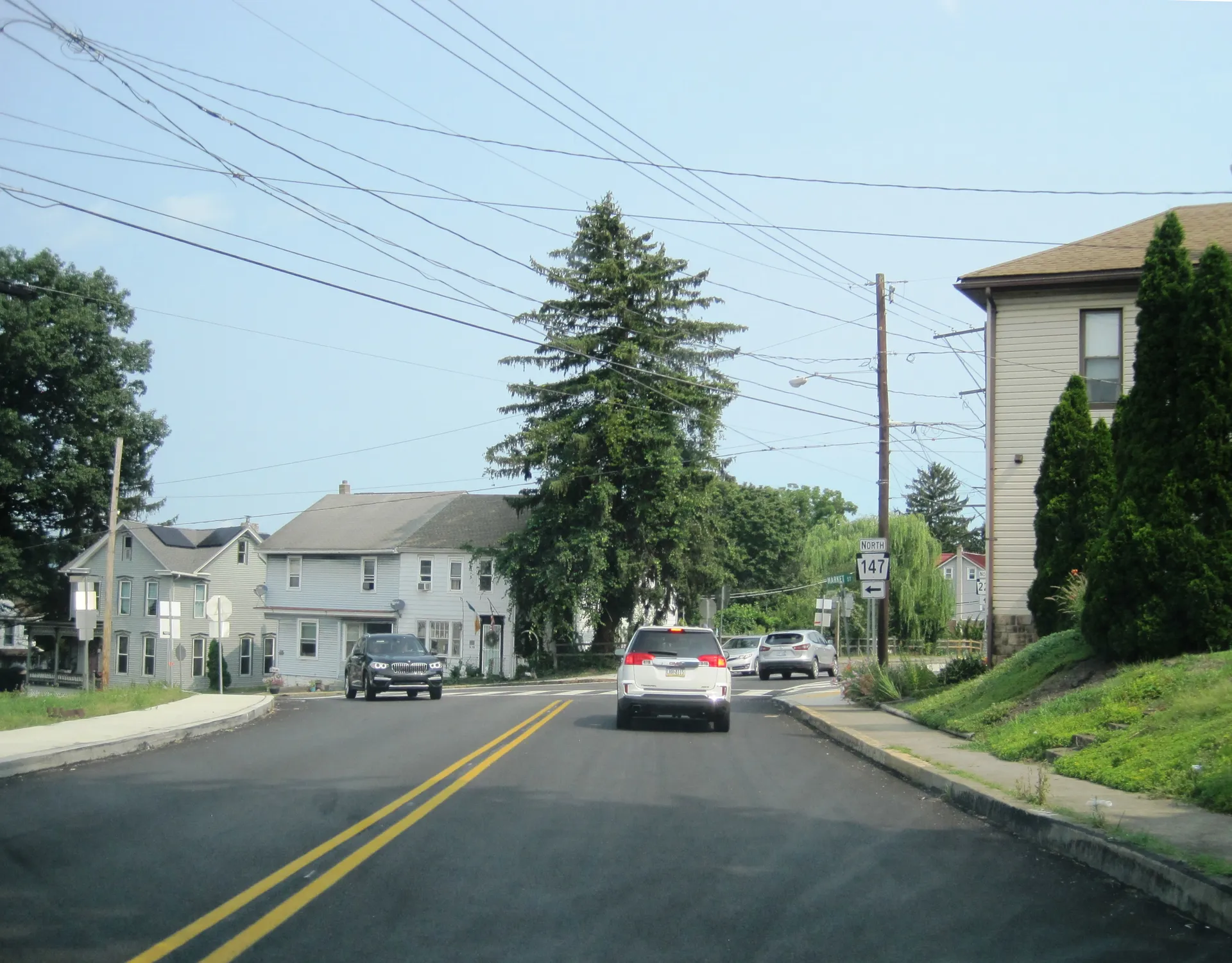 Fourth Street in Halifax approaches Market Street where Routes 147 and 225 split, lined with houses and tall evergreens.