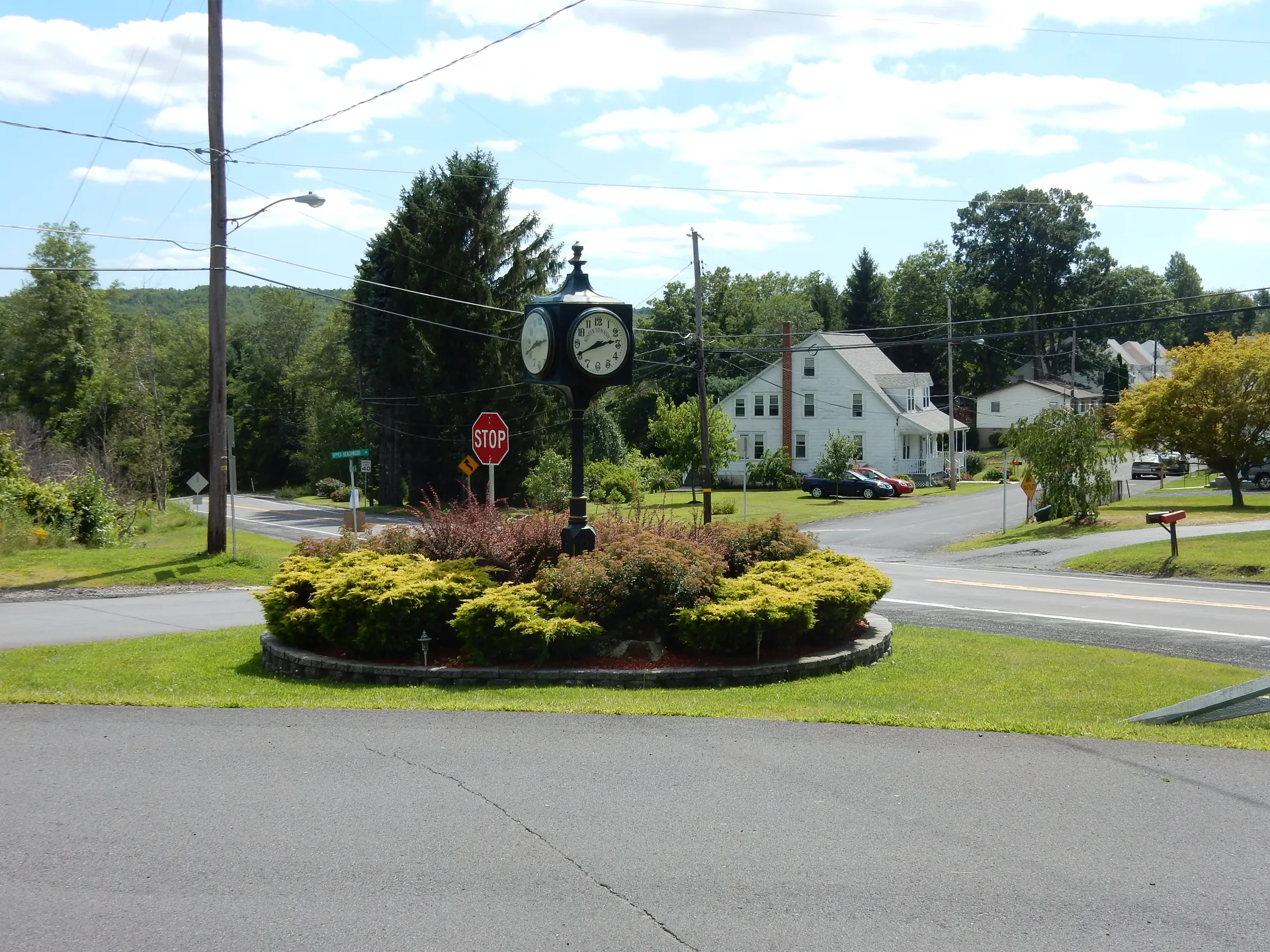 A floral island with a decorative street clock marks the corner of Sunbury Road and Upper Beechwood Avenue in Buck Run, Foster Township.