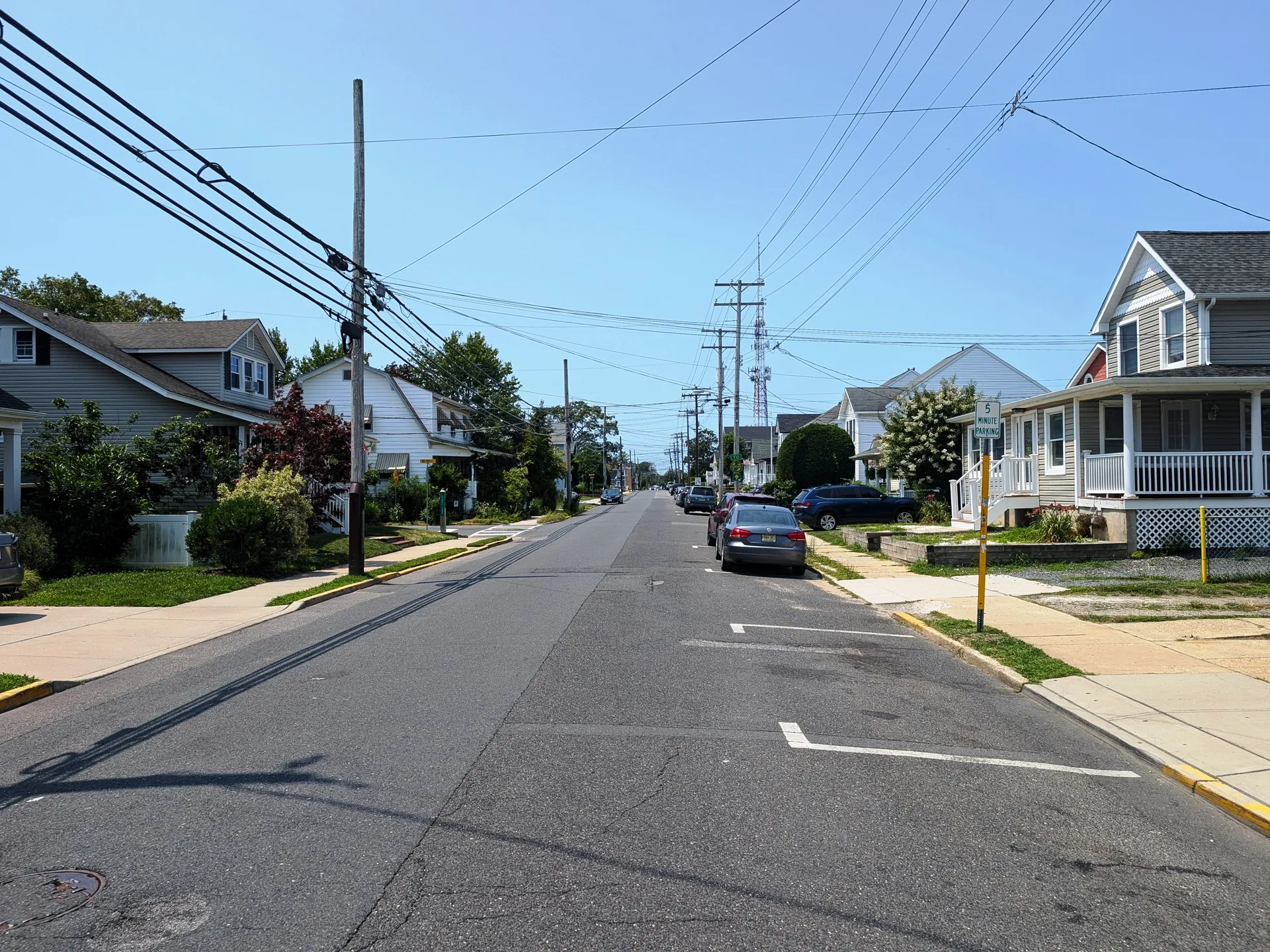 Heading west on 18th Avenue in Lake Como, a sunny residential street passes small homes, front lawns and parked cars.
