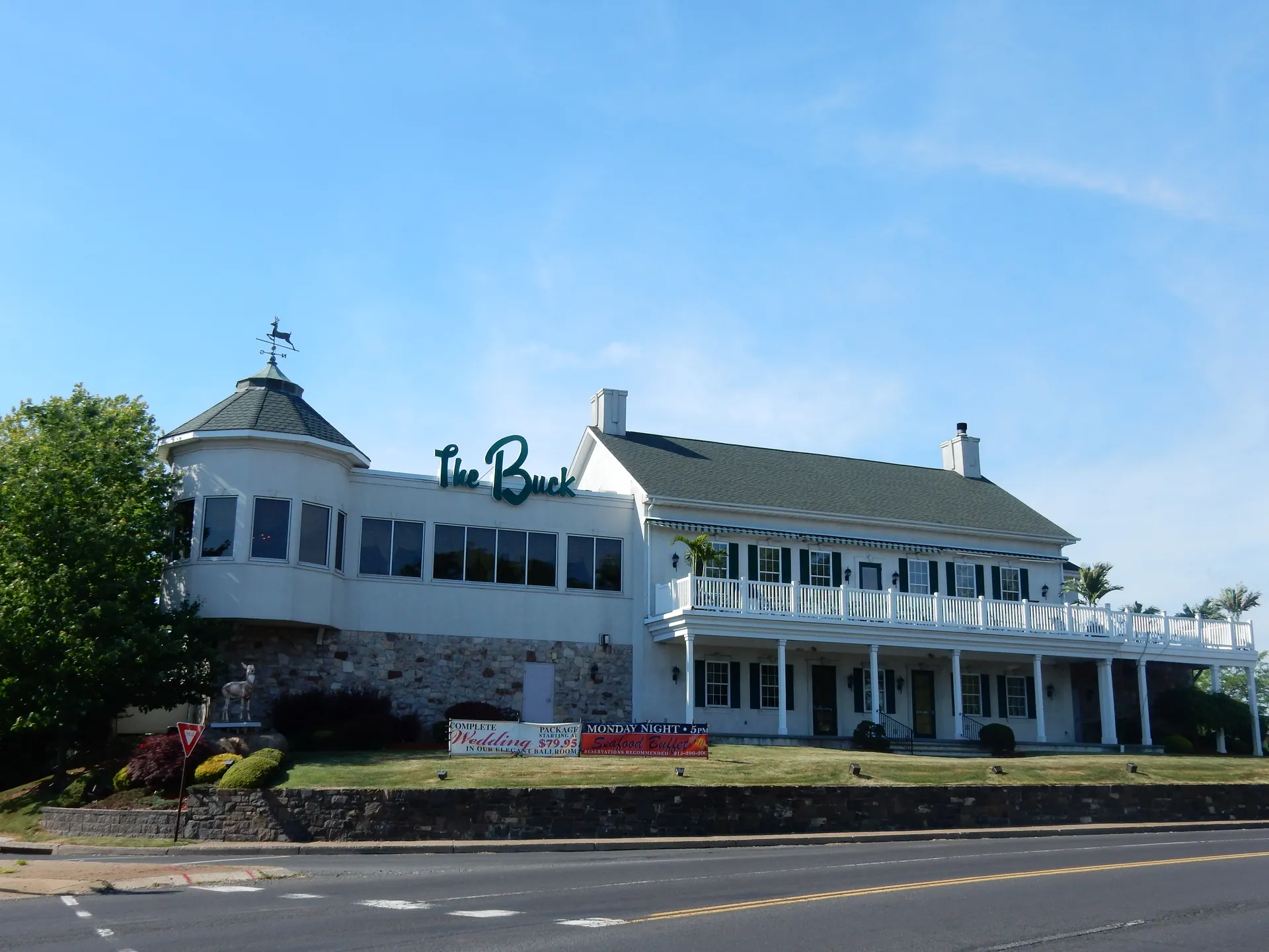 The Buck Hotel in Feasterville is a large white building with a decorative cupola, wide porches and flower beds.