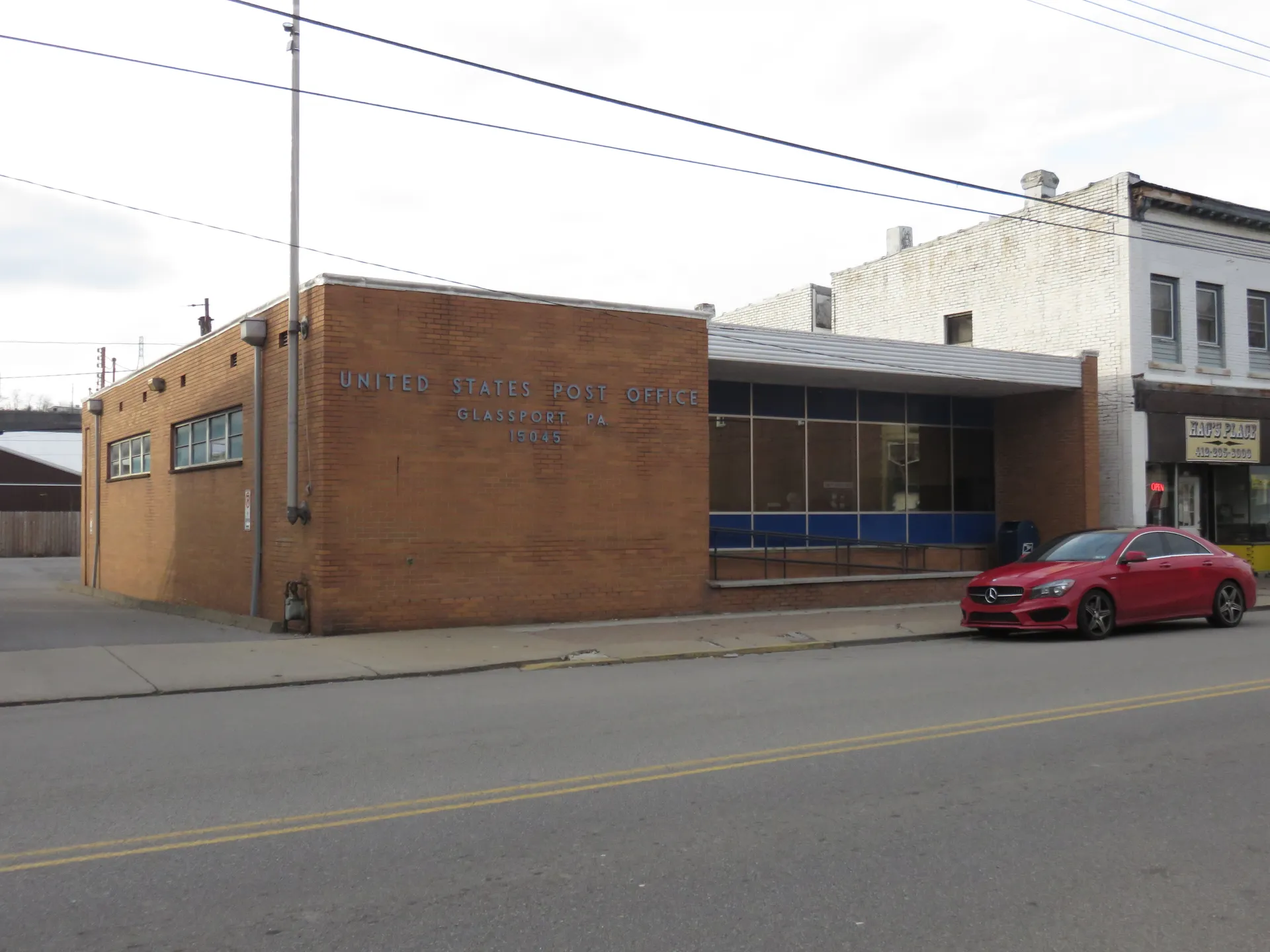 The Glassport post office is a brick building with a flat roof and blue trim on a downtown corner.