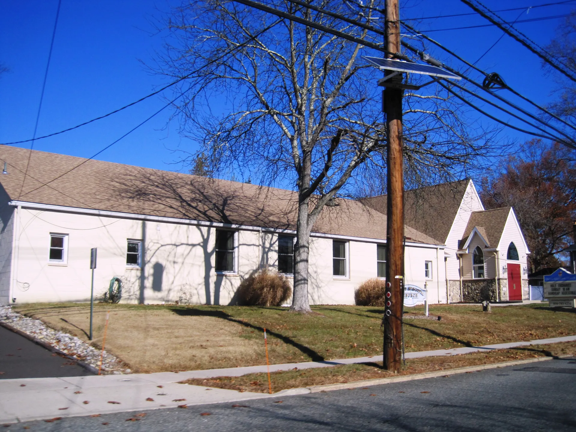 Christ Episcopal Church in Magnolia is a low white church building set behind a lawn and a tall utility pole.