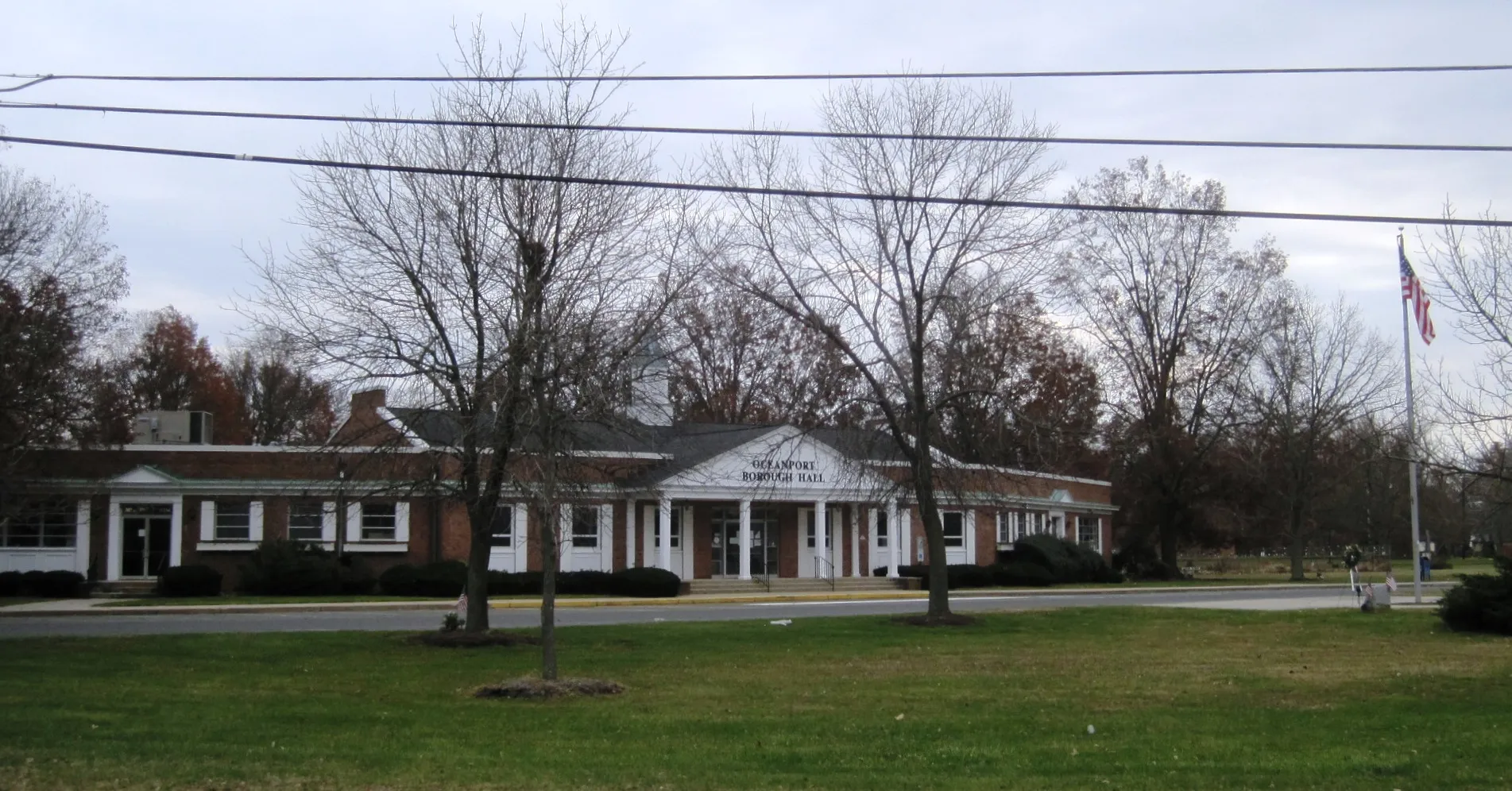 Oceanport borough hall is a white-columned building with a broad roof set back on a leafy lawn.