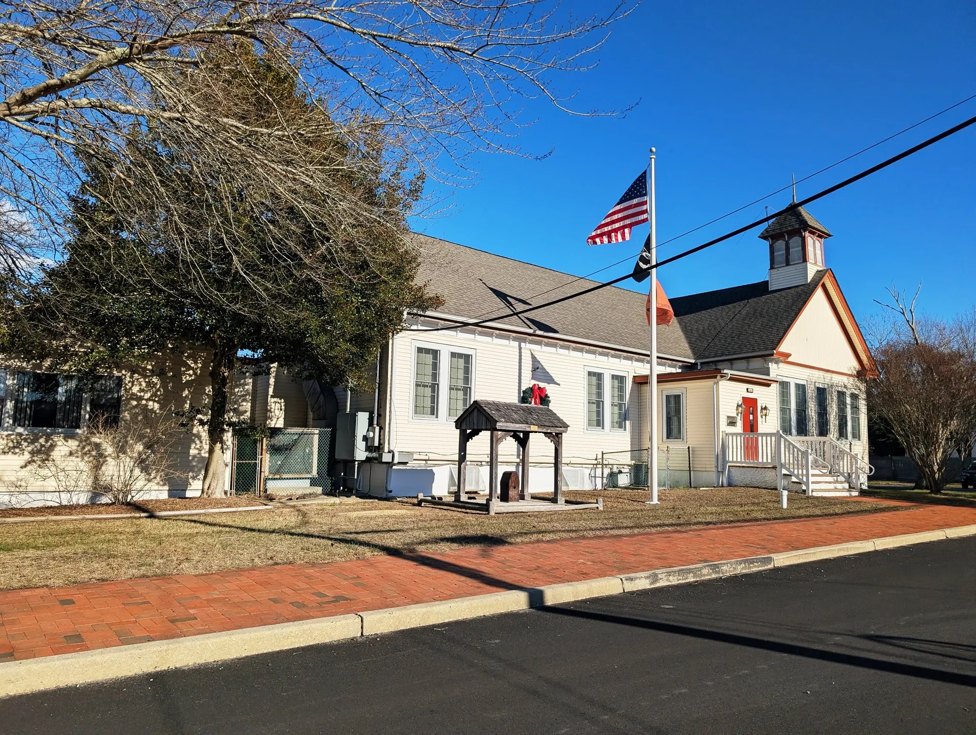 Eagleswood Township's municipal building is a white clapboard structure with a flag, a small gazebo-roofed well and a brick walk.