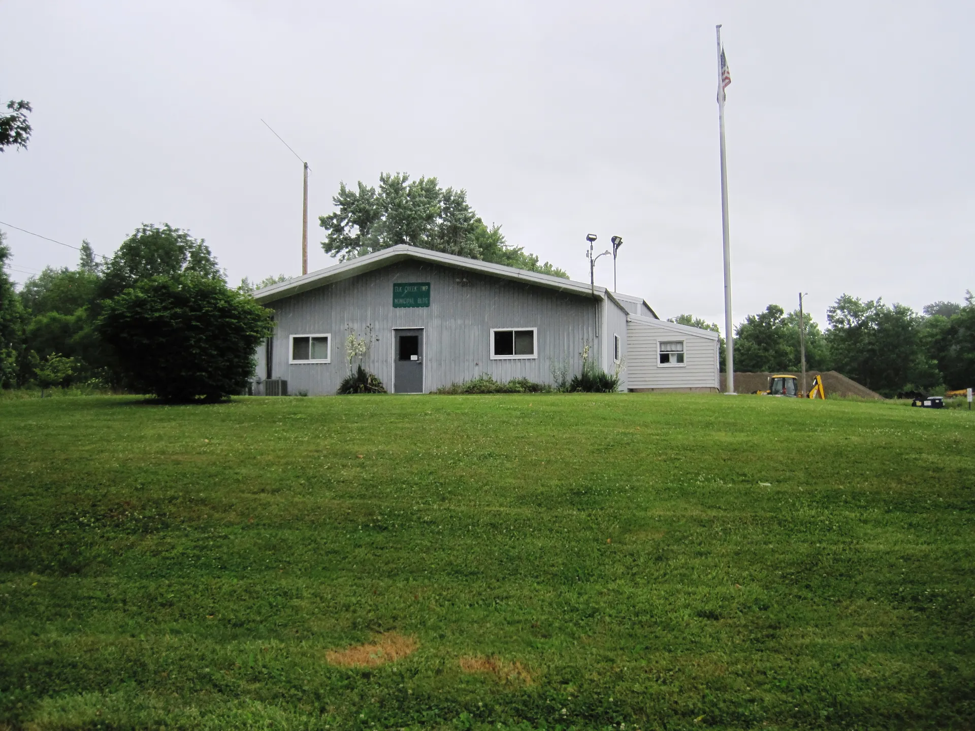 Elk Creek Township's municipal building is a small white single-story structure with a flagpole beyond a mowed lawn on High Street.