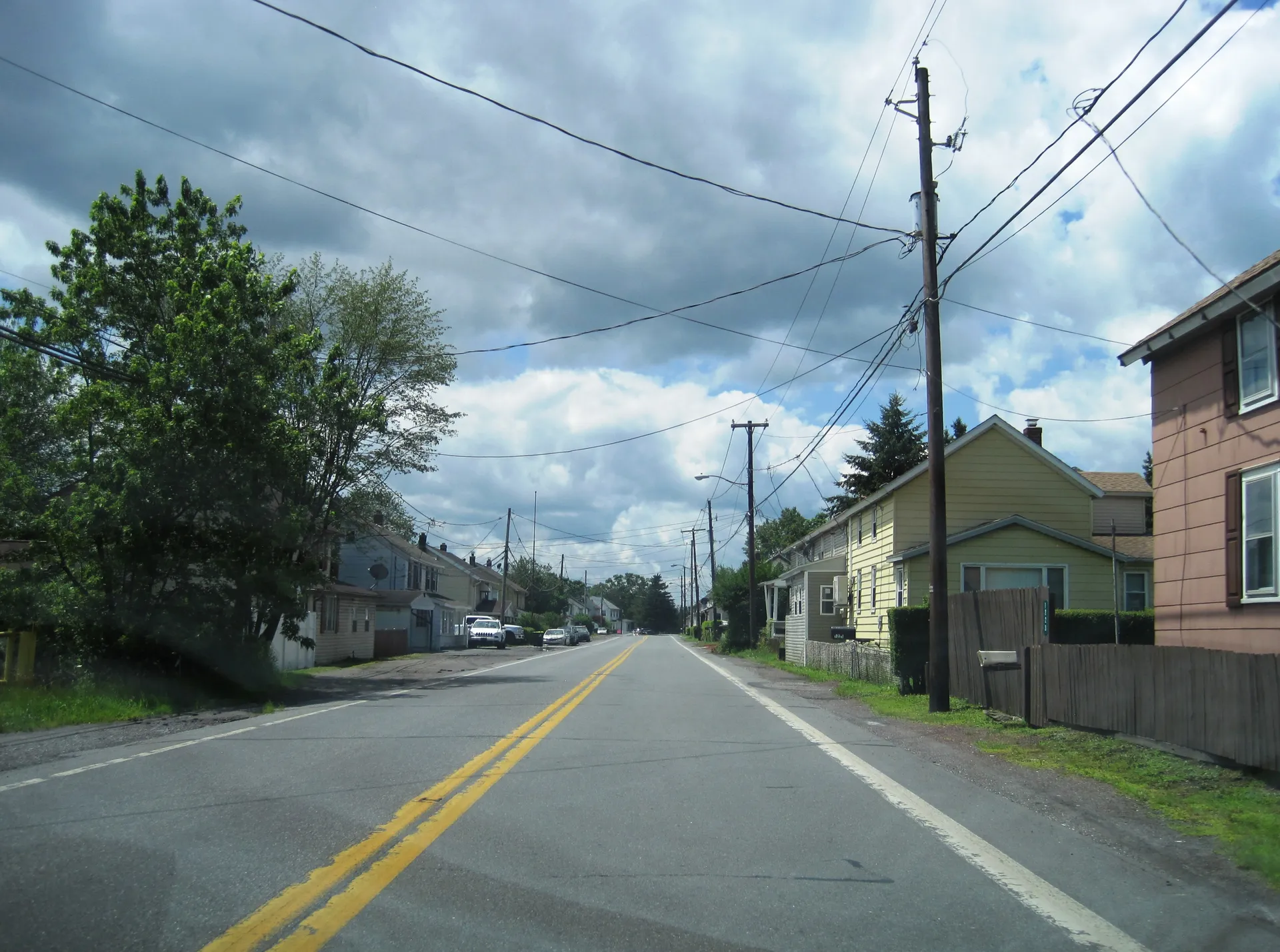 Route 940 sweeps through Harleigh in Hazle Township, passing modest homes, a brick house and roadside utility poles.