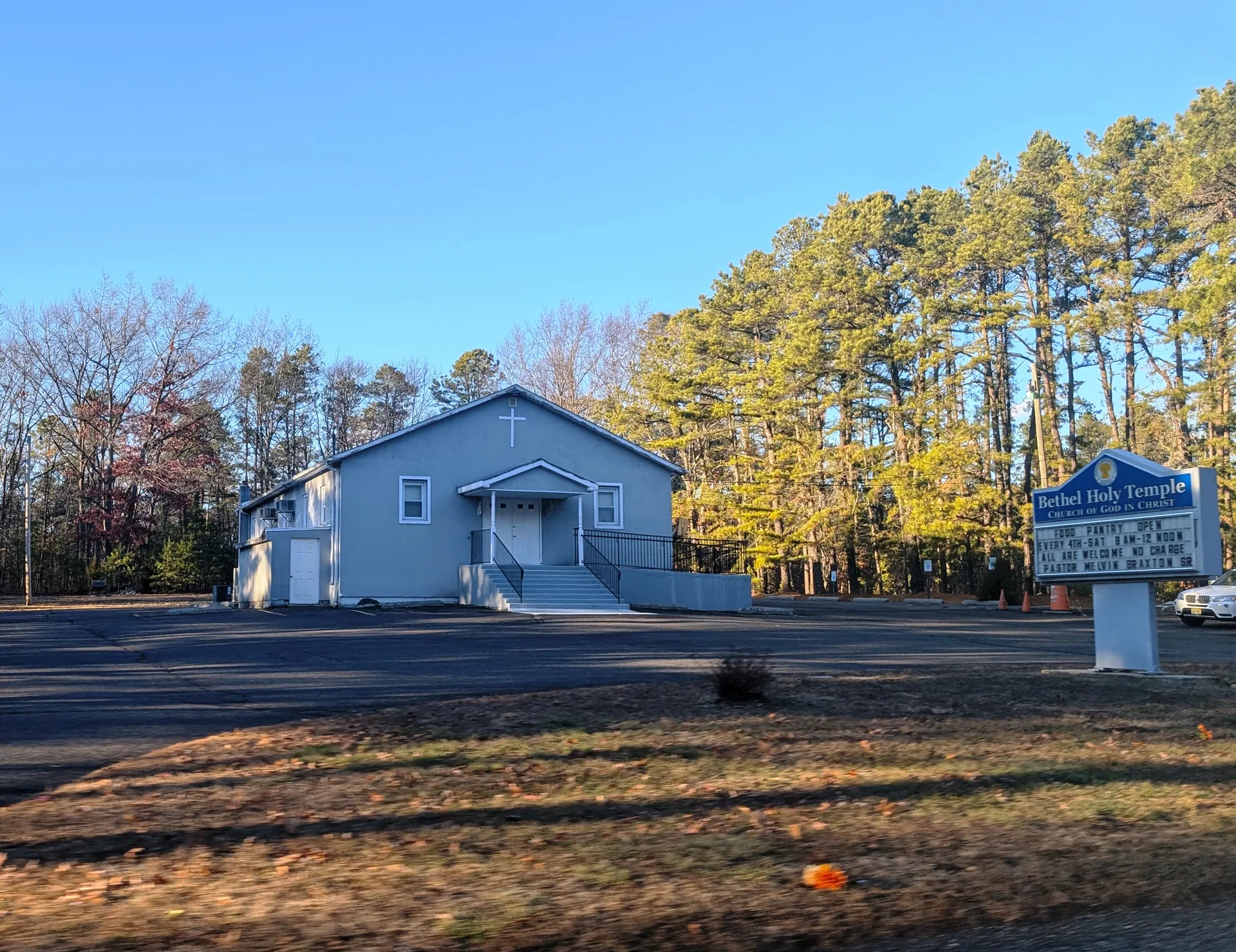 Bethel Holy Temple Church in Newtonville is a small pale blue church on a lawn bordered by autumn trees.