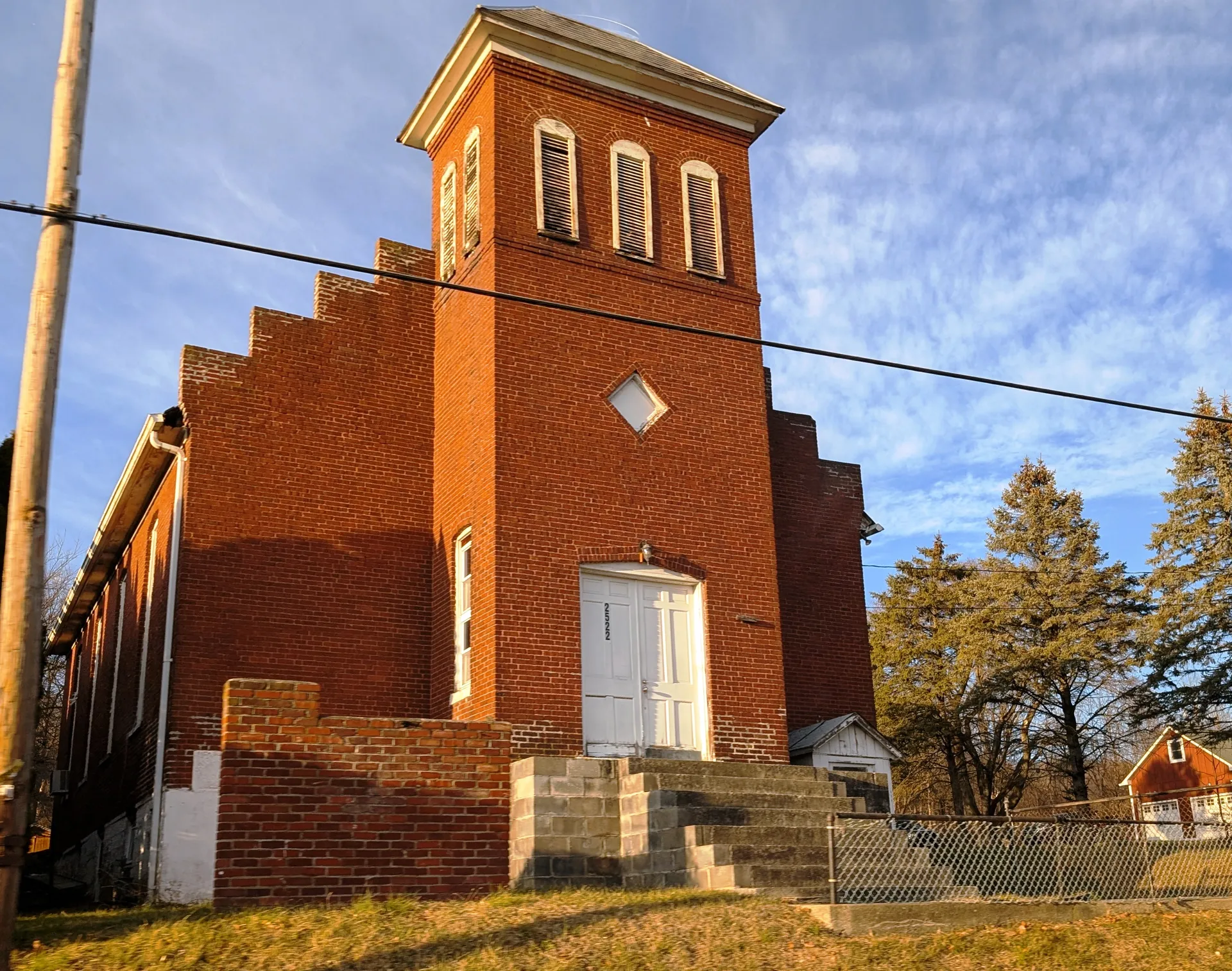 The former church in New Village is a red brick building with a tall belfry and a white front door.