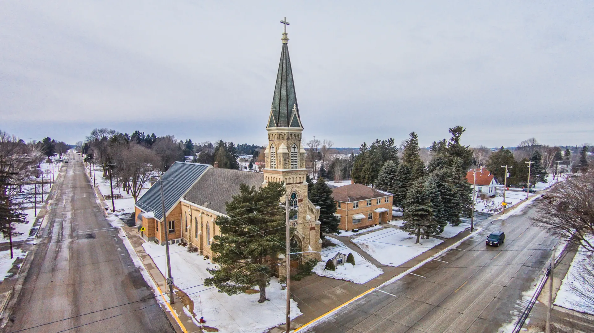 Holy Cross Church steeple rising over a snowy street in Mishicot, Wisconsin.