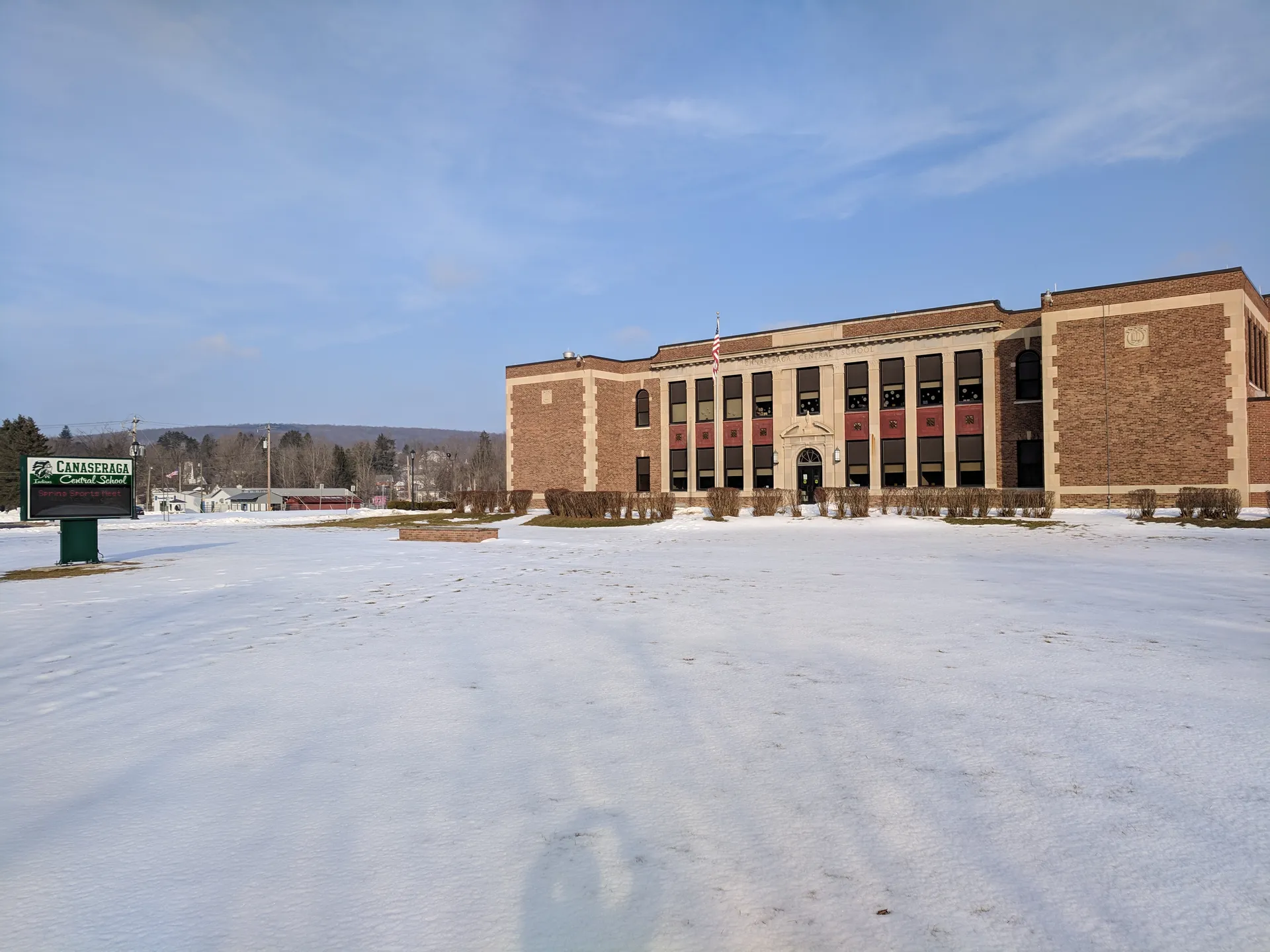 Canaseraga Central School building beyond a snowy field in Canaseraga, New York.