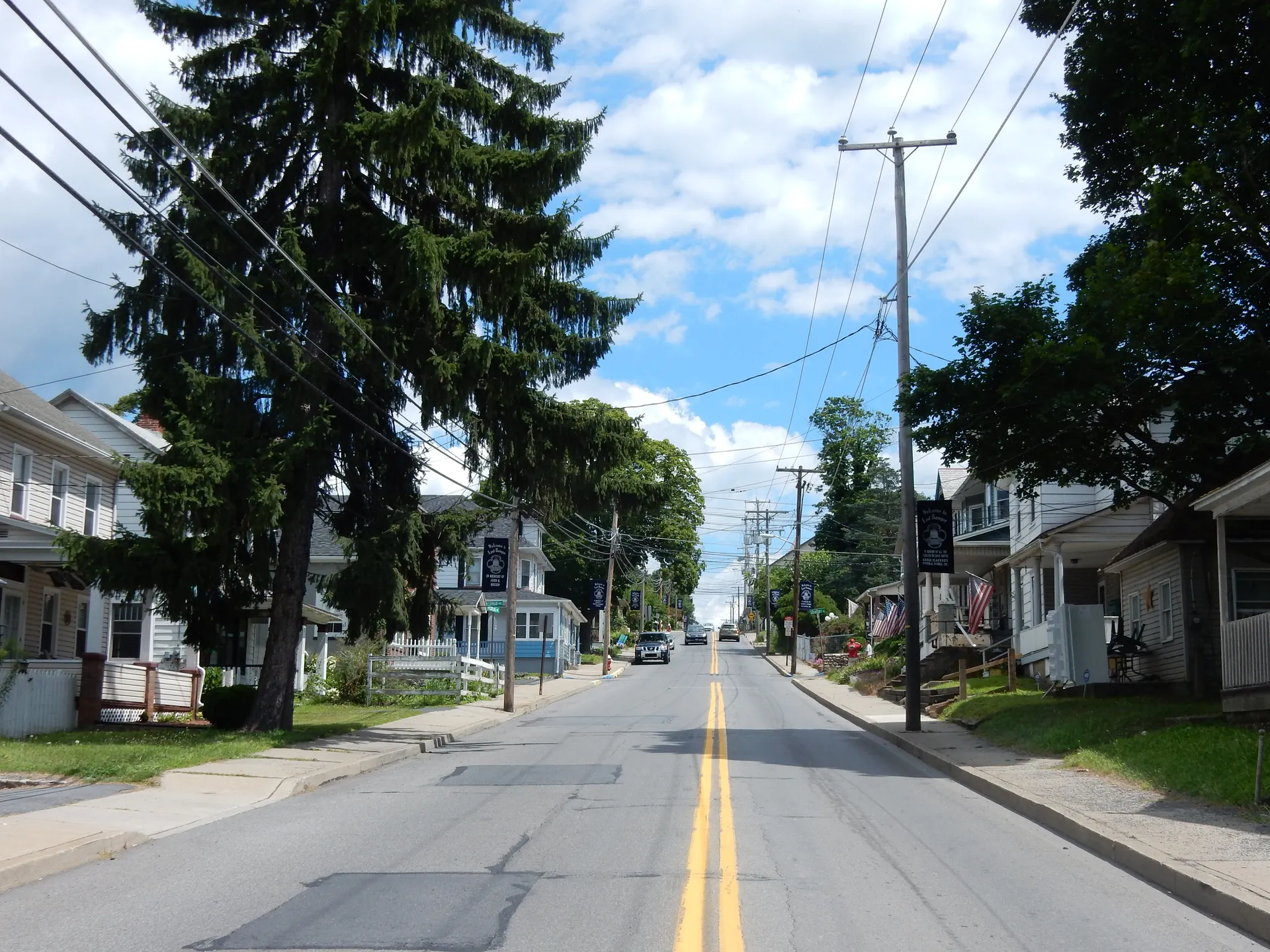 West Central Avenue in East Bangor runs east past tall evergreens and porch-fronted homes on a sunny day.