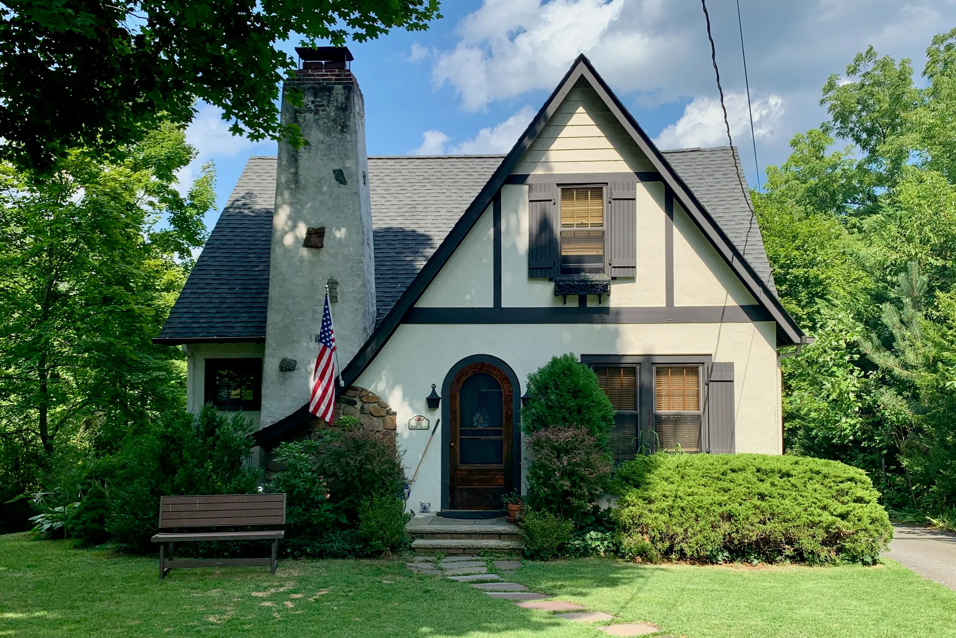 The house at 520 Lyons Road in Liberty Corner is a cream Tudor-style cottage with a steep gable and a flag.