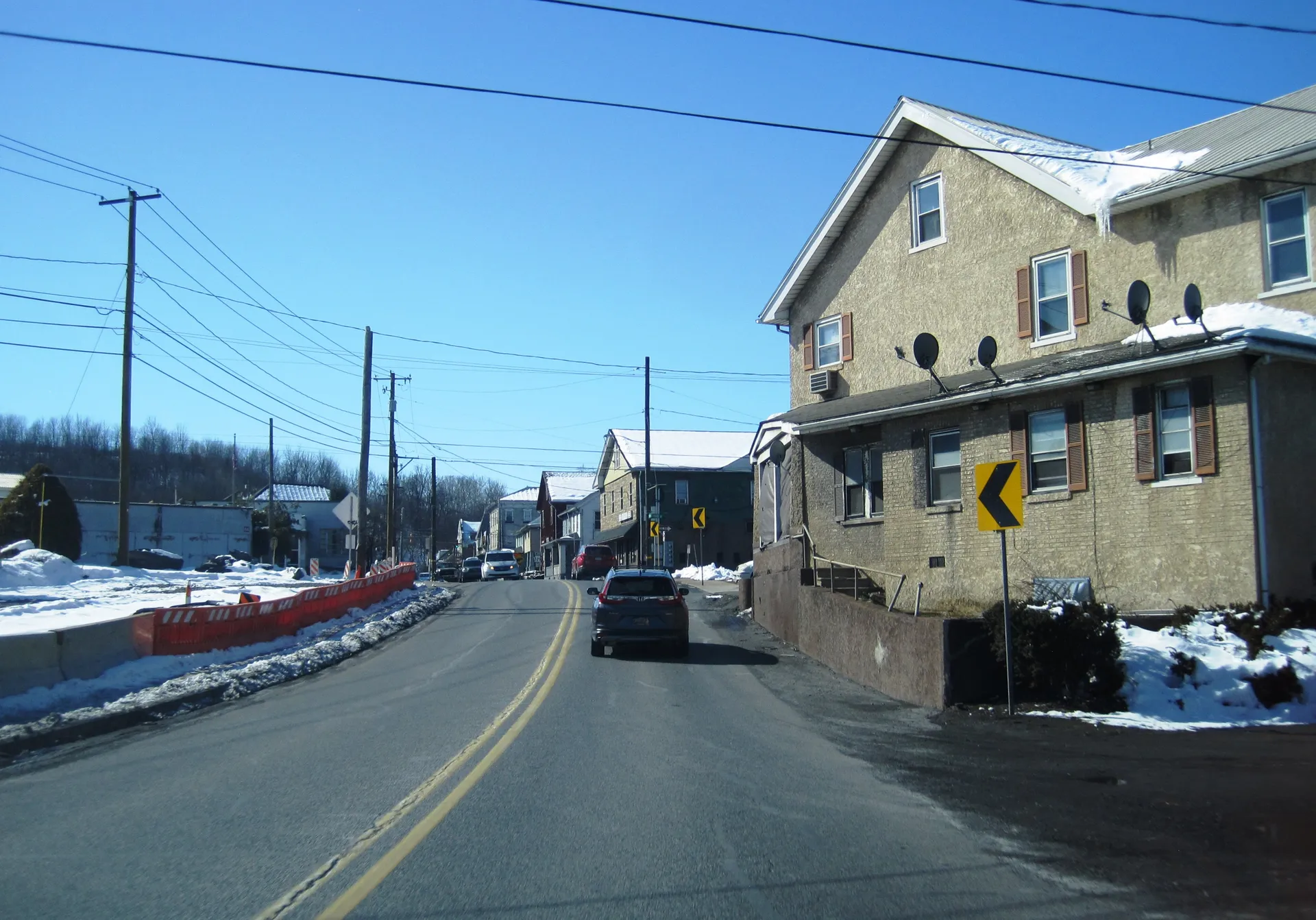 Main Street (Route 329) curves through Cementon in Whitehall Township, passing a stone building with a porch and a row of older homes.