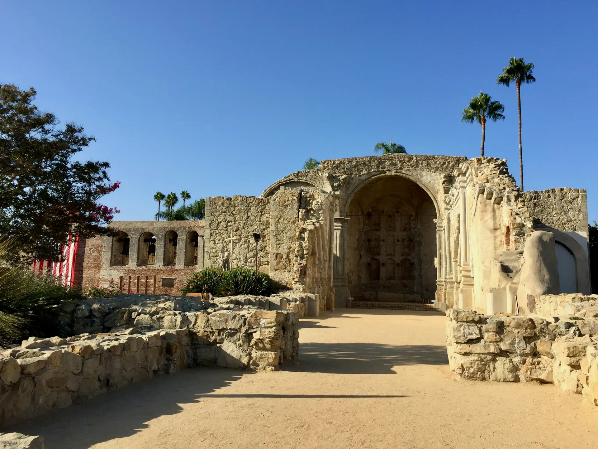 a stone building with palm trees in the background, San Juan Capistrano, CA.