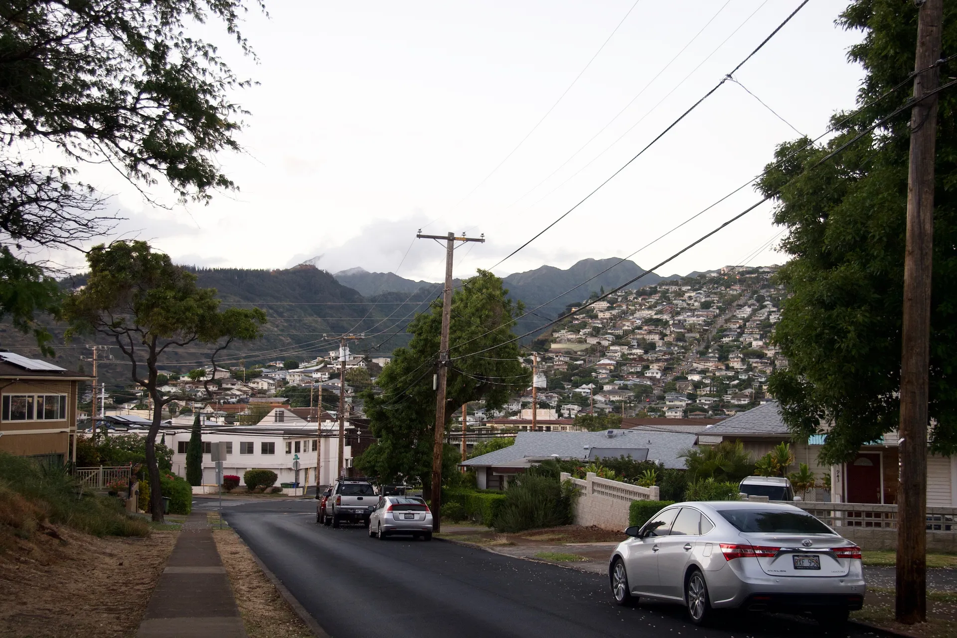 Homes and a sloping residential street on Ocean View Drive in Kaimukī, with mountains in the distance, photographed June 1, 2021.