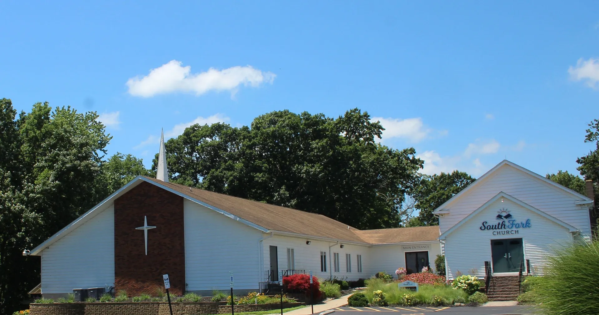 South Fork Church in Cotton Hill Township is a white single-story building with red flowering shrubs, set against tall trees.