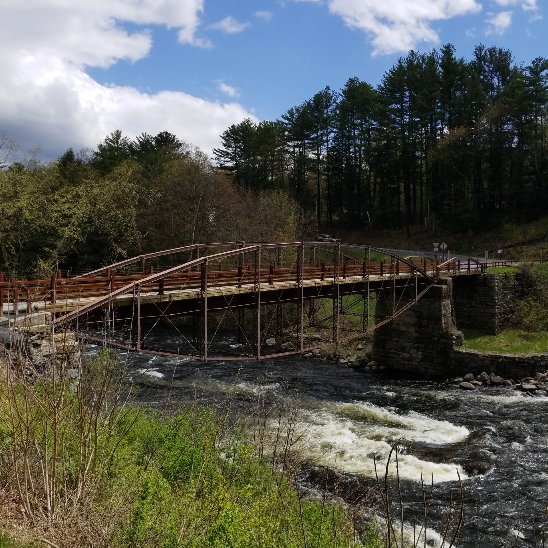 Historic Hadley Bow Bridge spanning a rocky river in Hadley, New York.