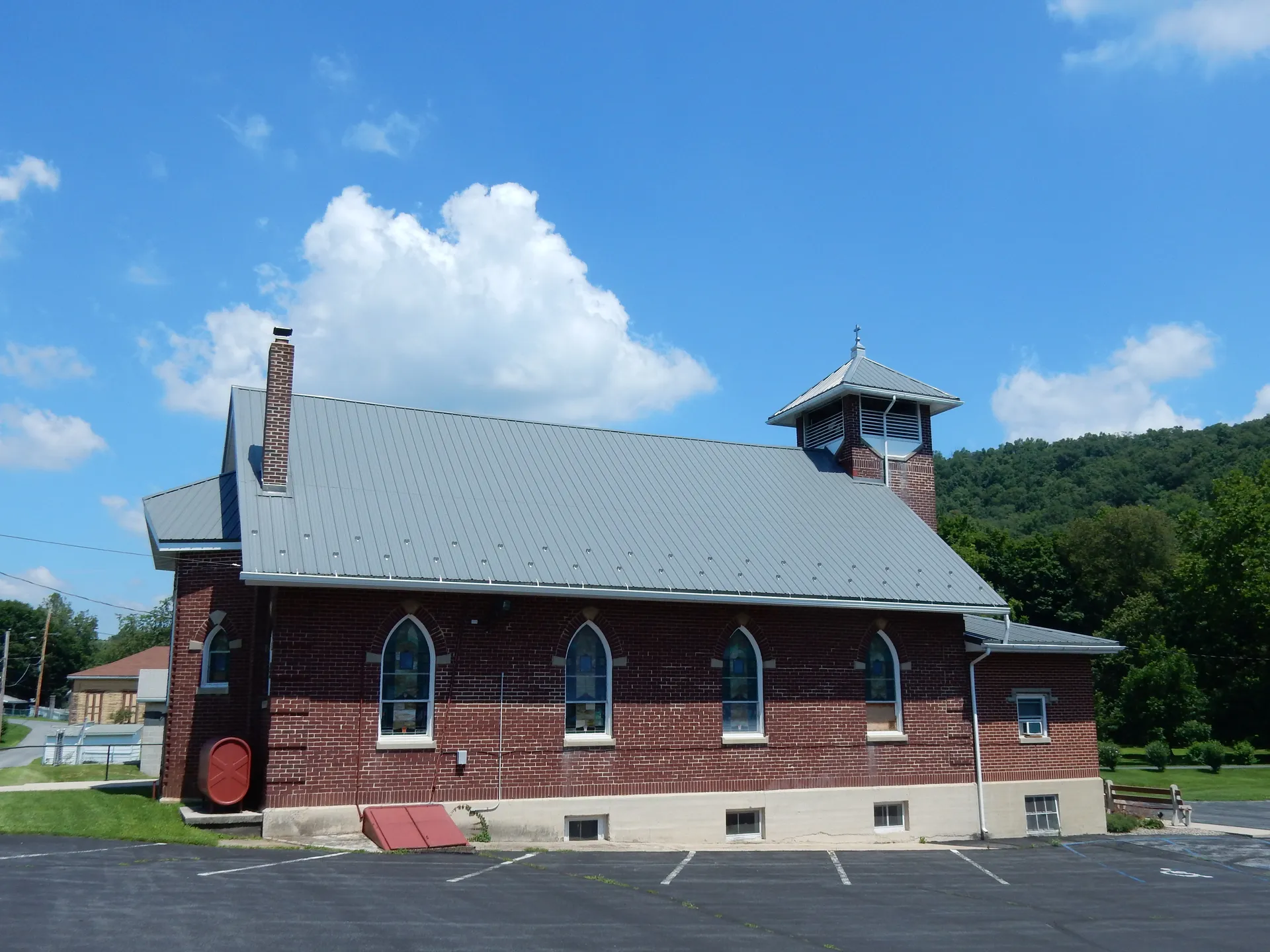 Faith United Church of Christ in Landingville is a red-brick church with a small belfry beside a forested hill.