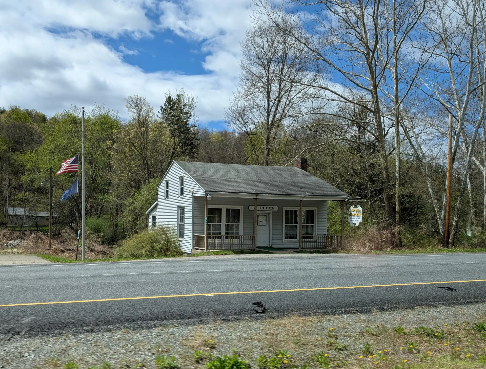 A small gray house-style building houses La Plume Township's offices, seen from U.S. Routes 6 and 11.