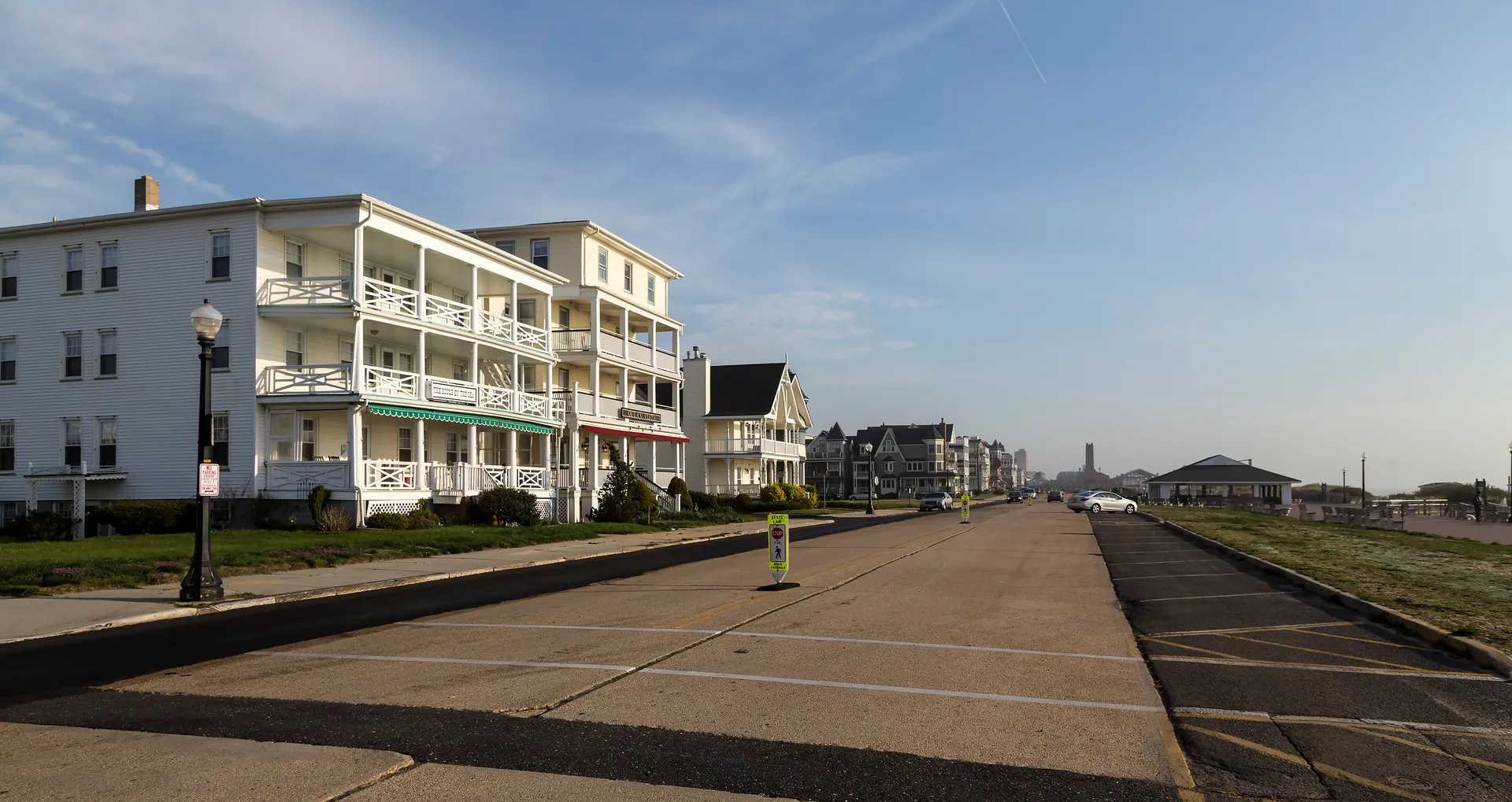 Grand Victorian hotels with stacked porches line Ocean Avenue in Ocean Grove, facing a wide promenade.