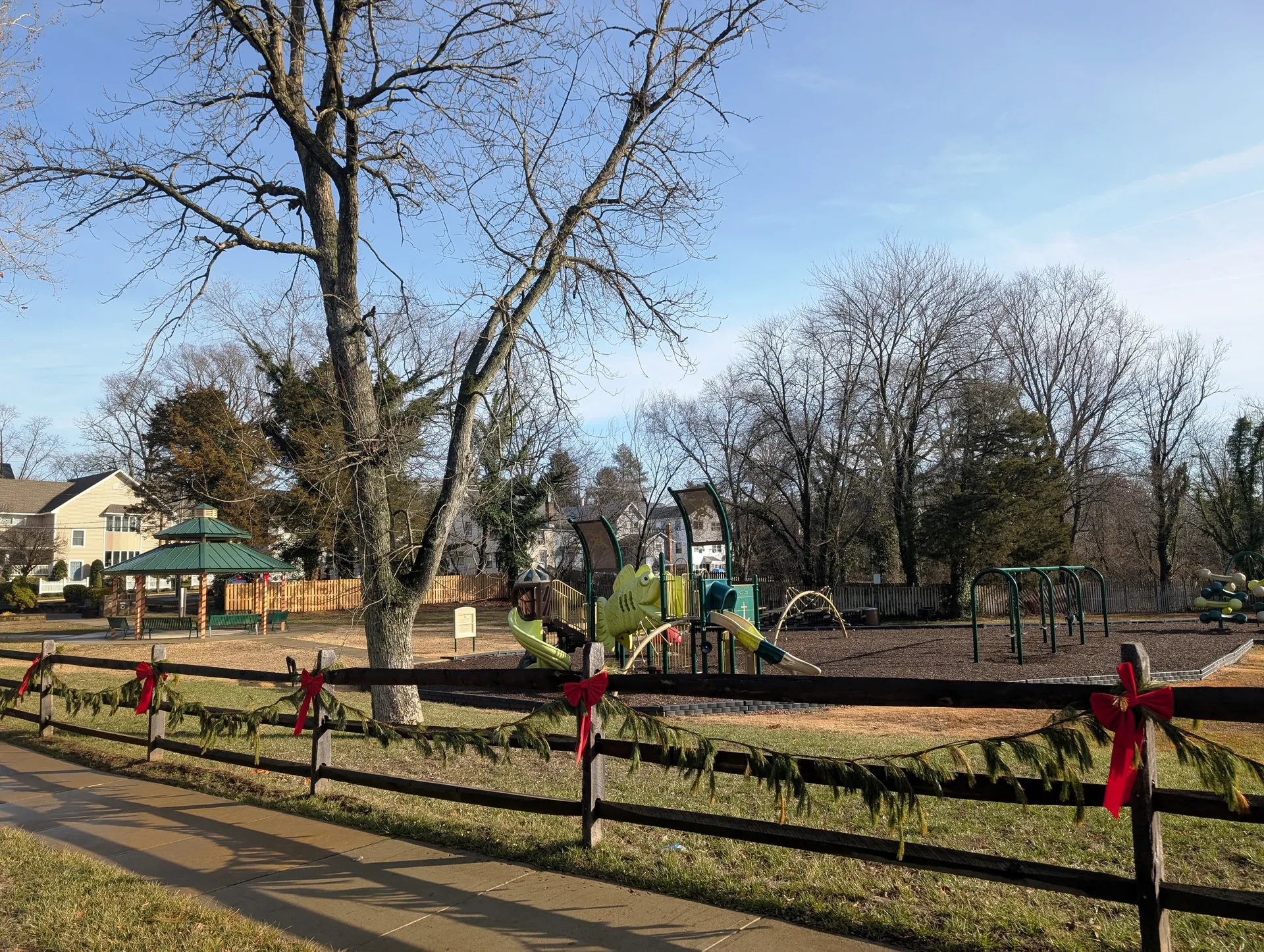 Mill Creek Park in Pemberton has a playground and red flowers along a rail fence beneath tall trees.