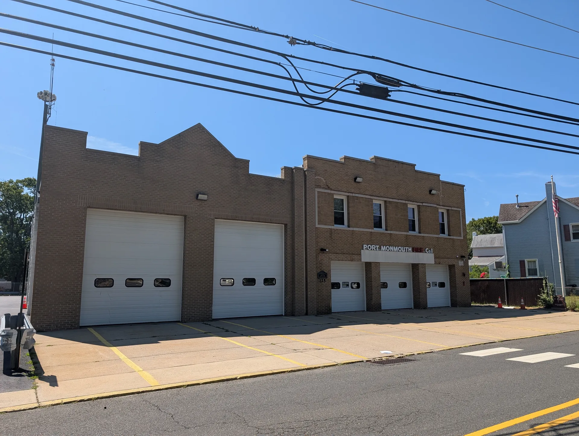 Port Monmouth Fire Company No. 1 is a tan brick firehouse with three white bay doors.
