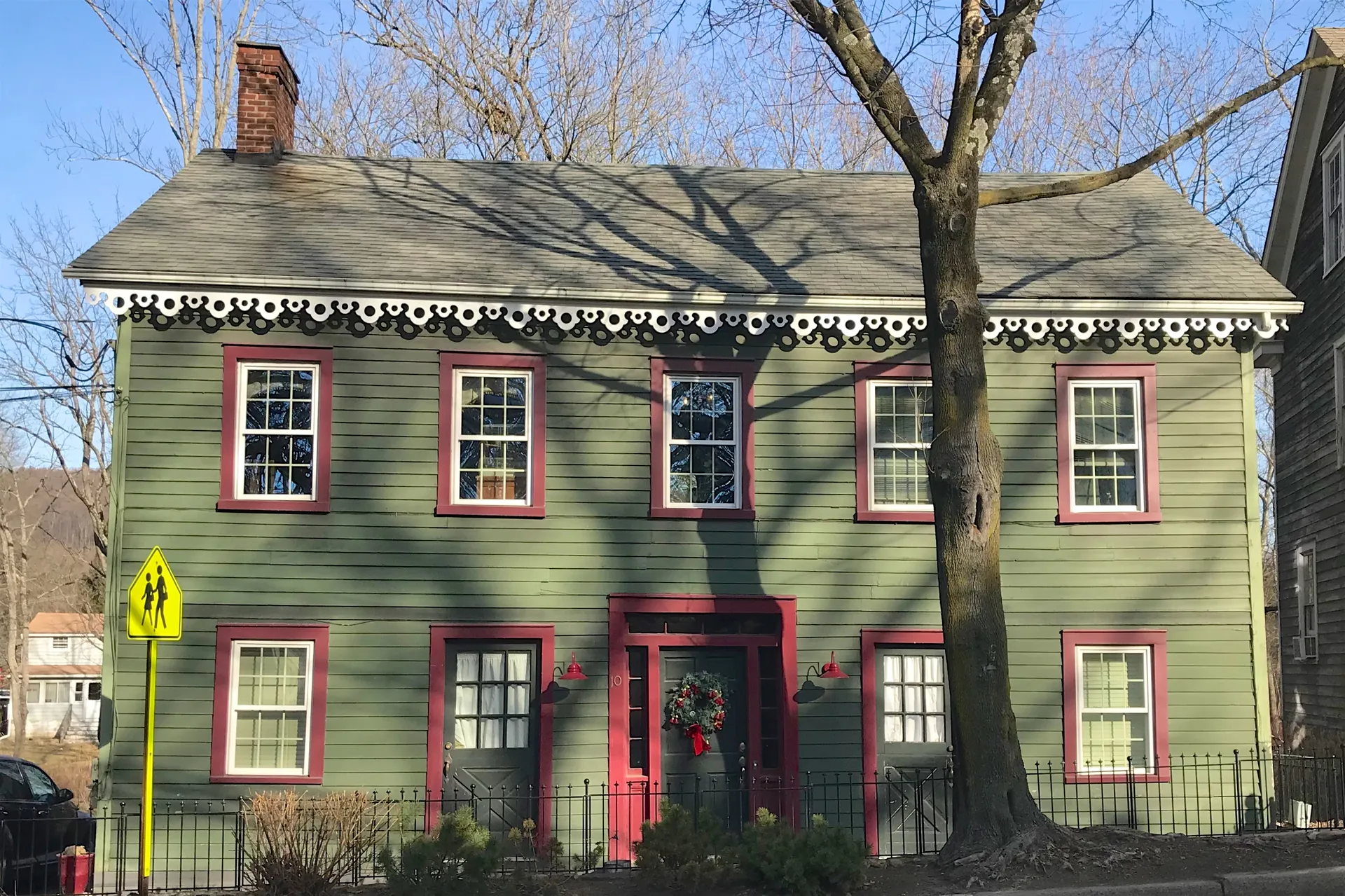 The house at 10 East Mill Road in Long Valley is a green clapboard building with red trim and a red door.