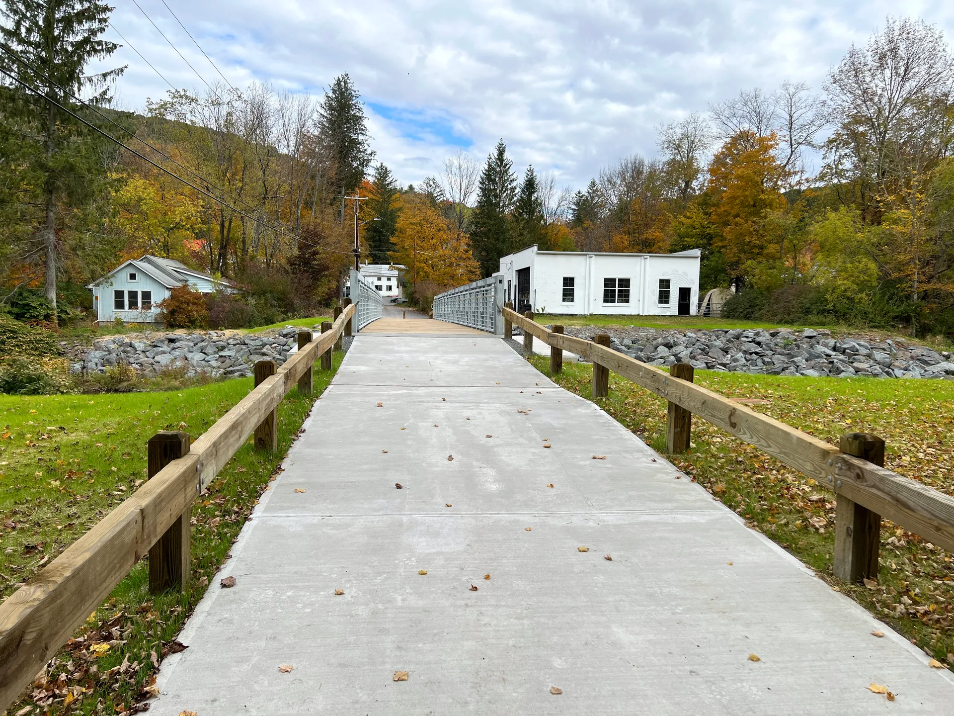 Pedestrian bridge path among autumn trees and homes in Fleischmanns, New York.