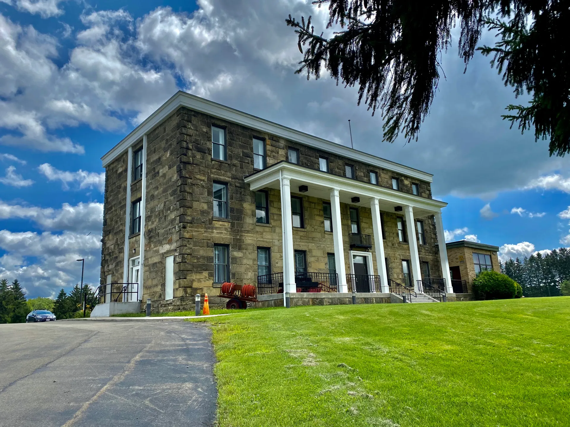 Historic stone Cattaraugus County Museum with a columned porch in Machias, New York.