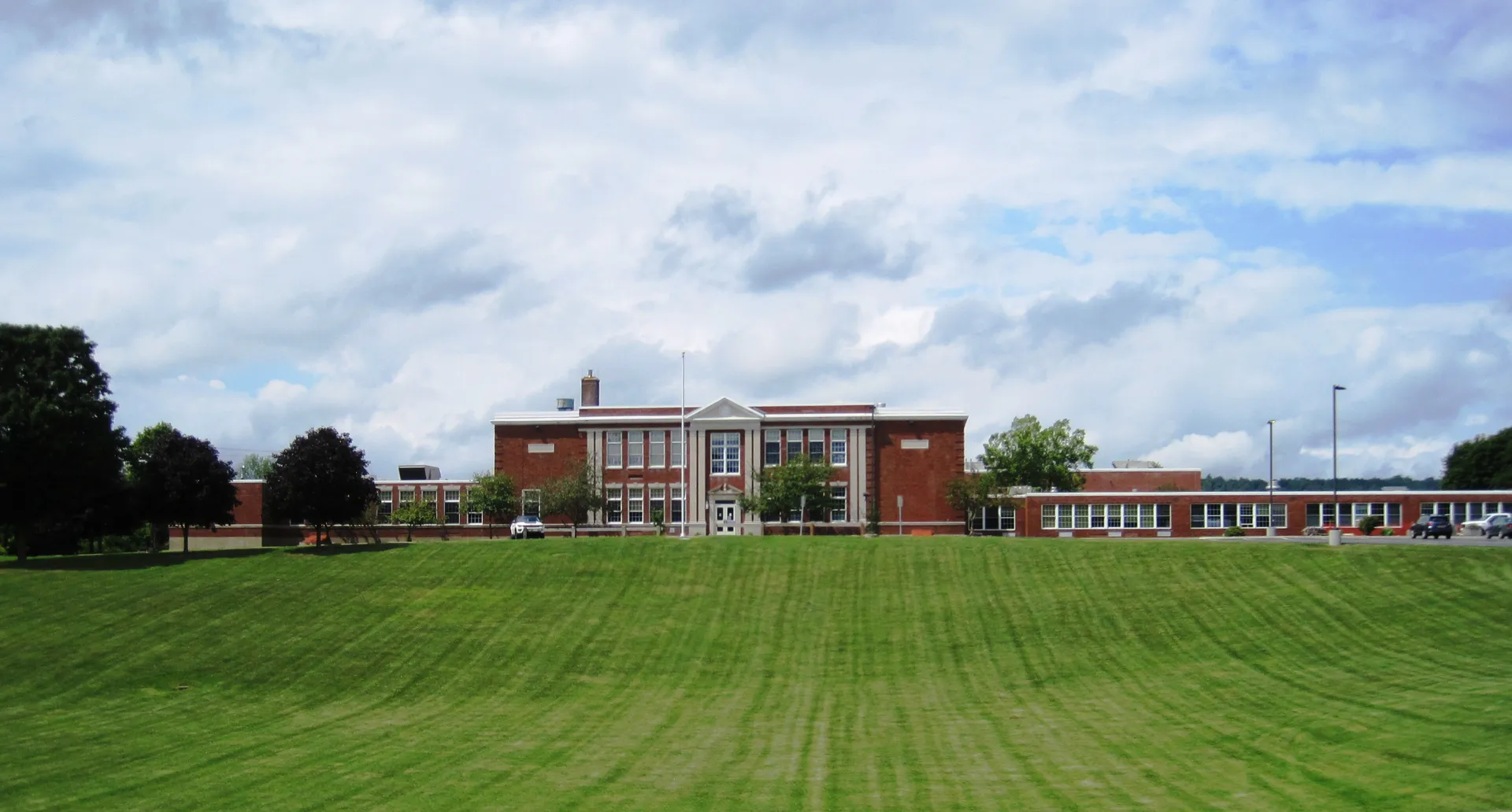 Brick Madison Central School beyond a wide lawn in Madison, New York.
