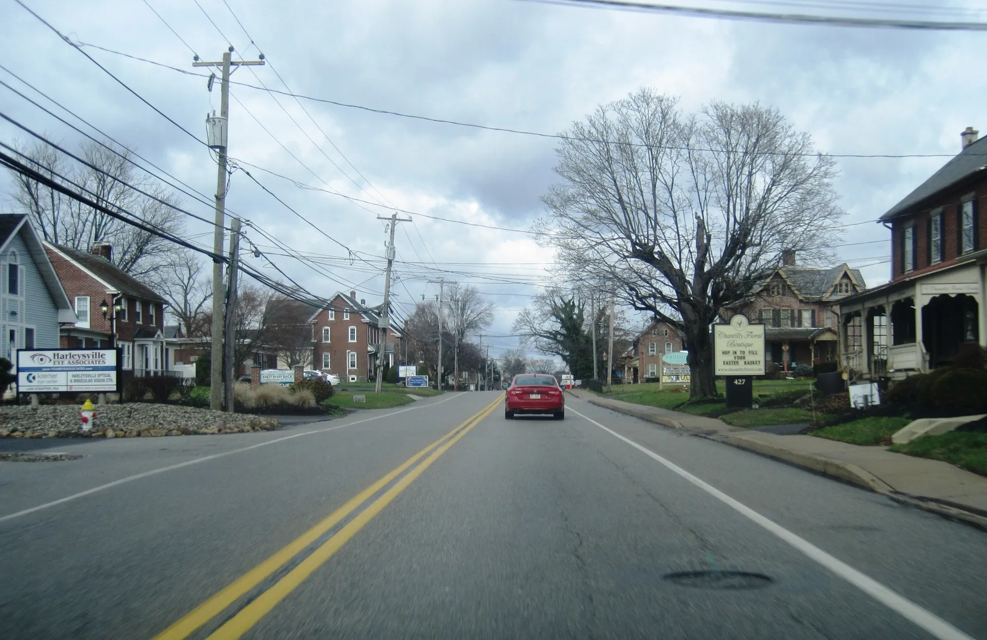 Main Street (Route 63) runs through the heart of Harleysville, flanked by homes, a bare shade tree and a red pickup.