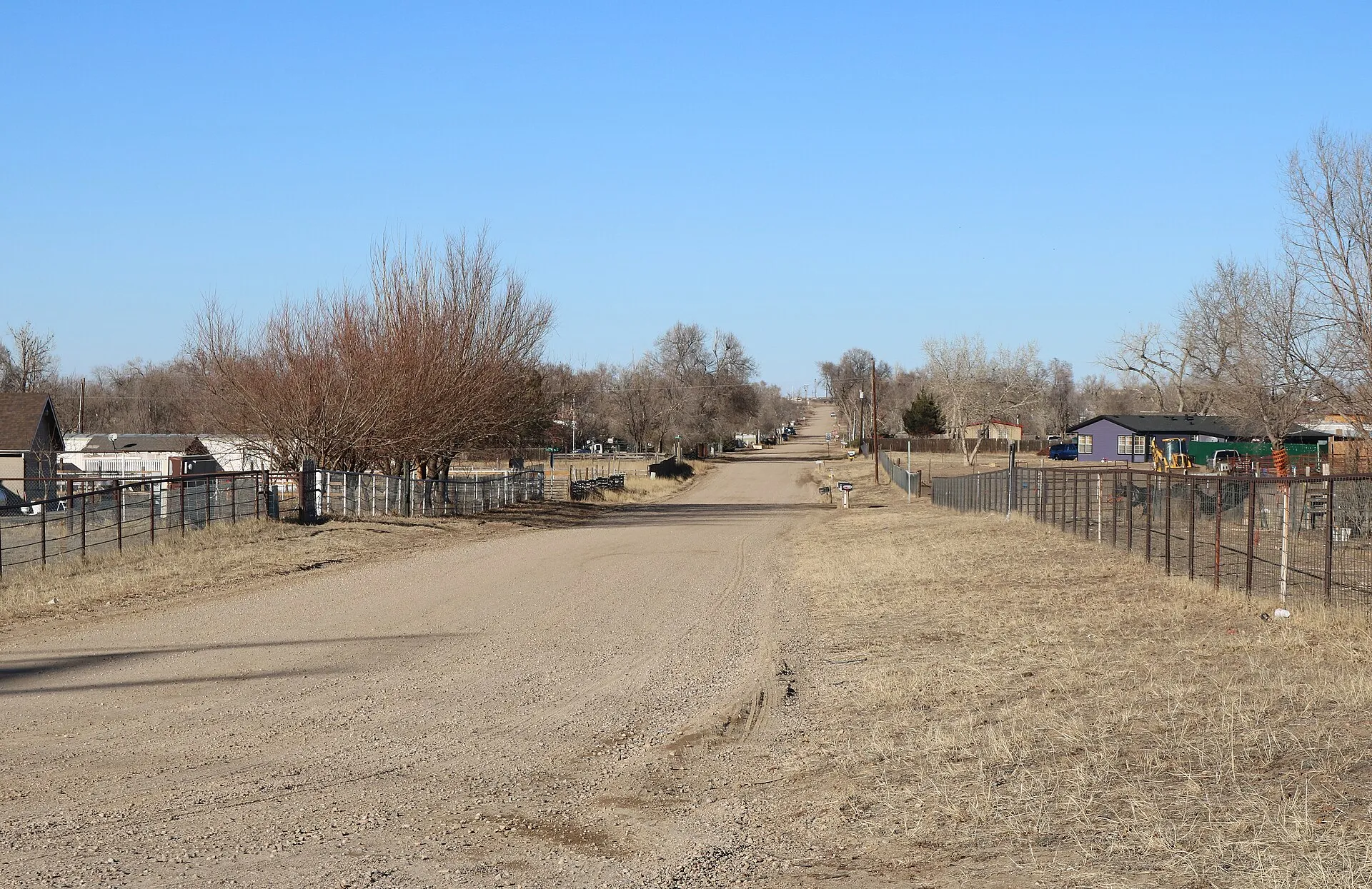 Dirt road and homes among trees in Aristocrat Ranchettes, Colorado.