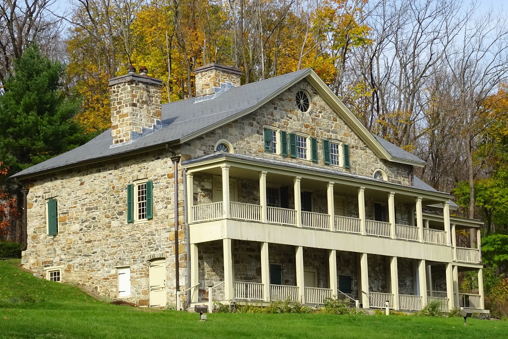 Shippen Manor in Oxford is a stone house with a two-story white-columned porch, framed by autumn foliage.