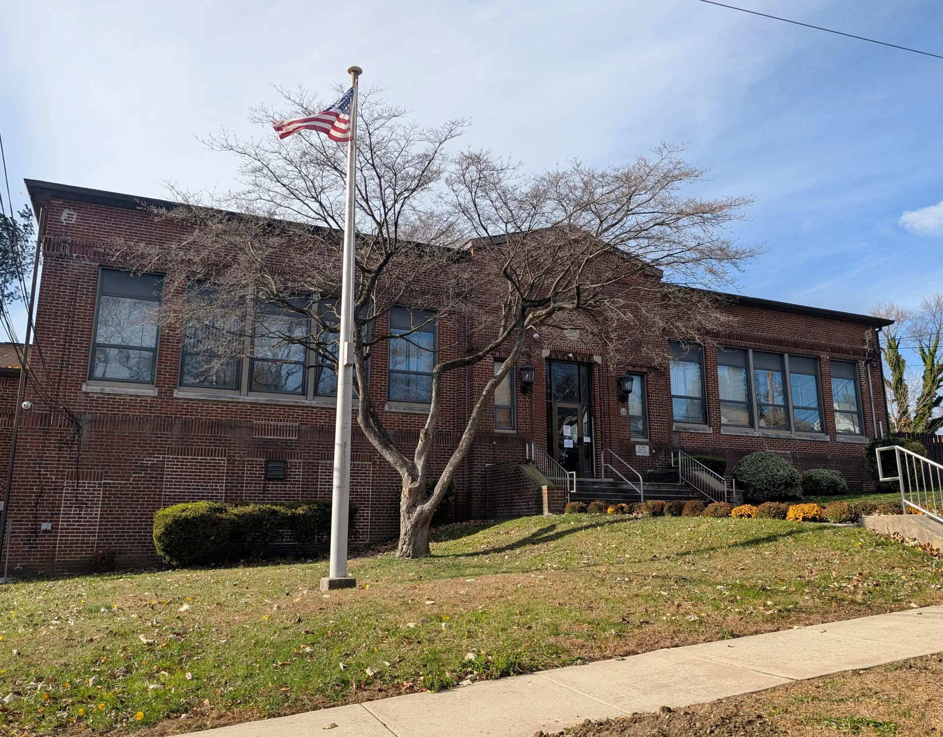 Glenolden Borough Hall is a long brick building with a flagpole and shade tree on East Boon Avenue.