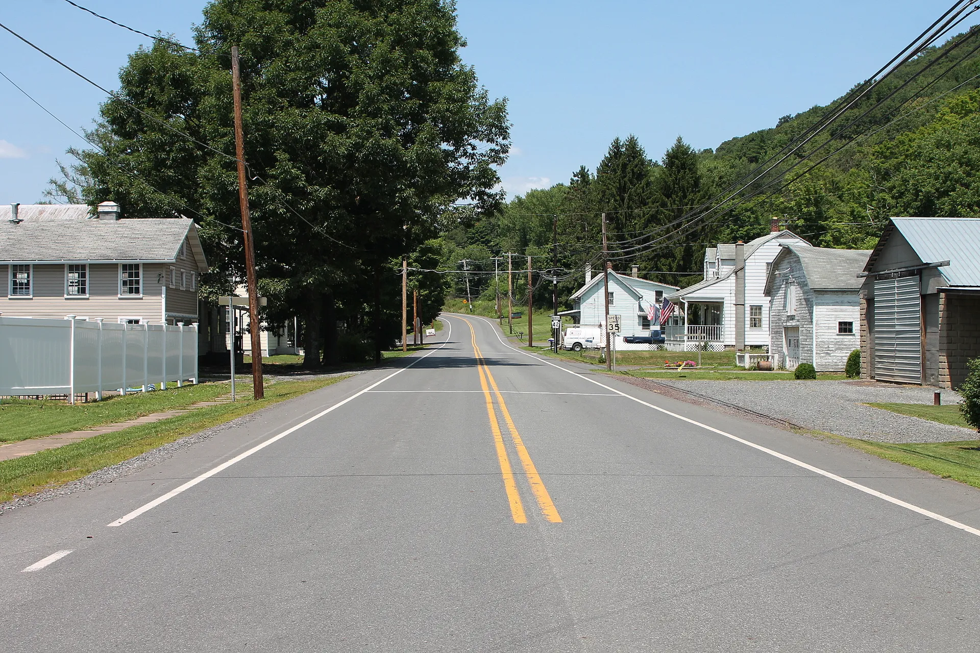 Route 42 passes white farmhouses and tall trees in the small Columbia County village of Eyers Grove.