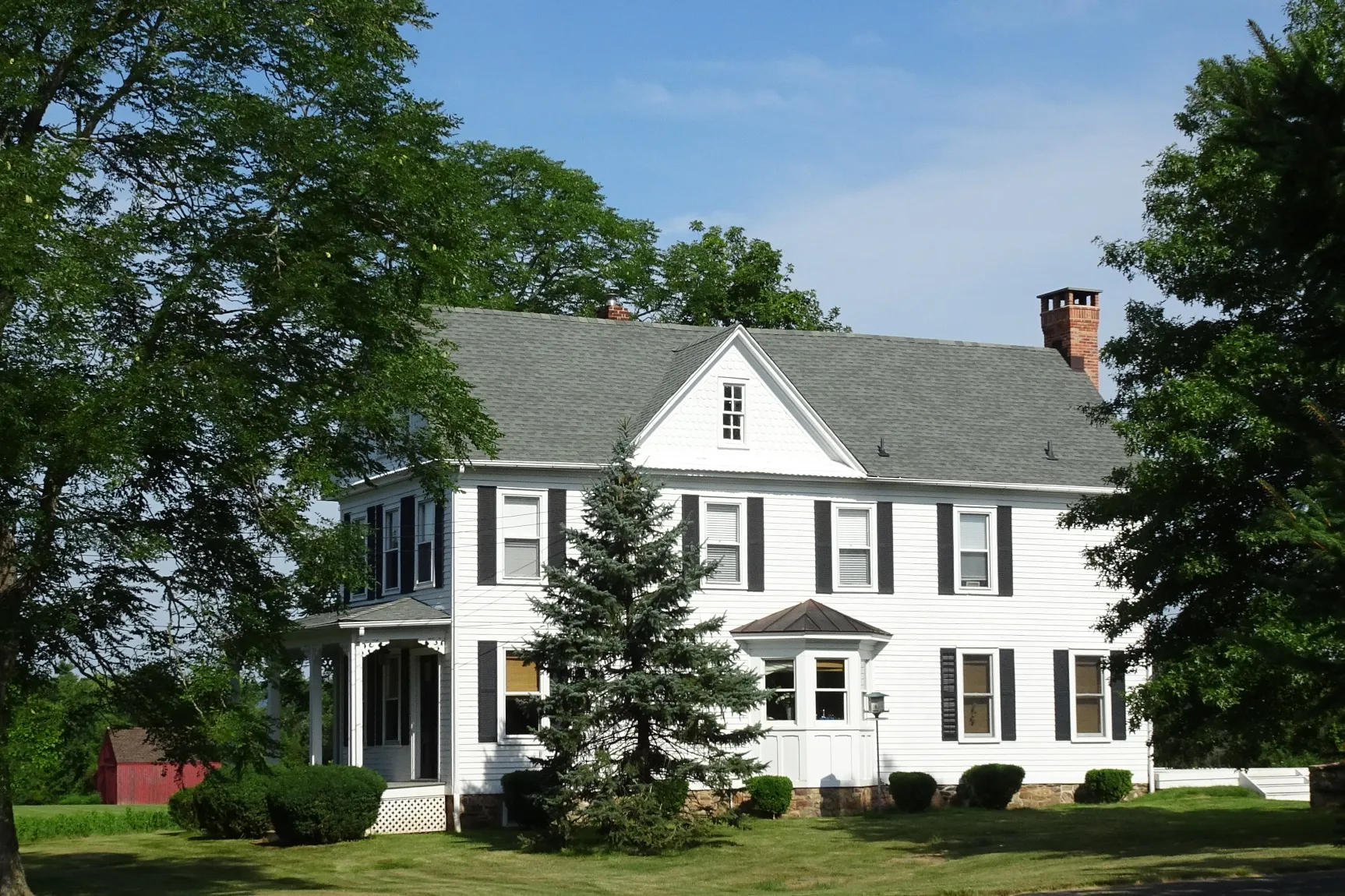 The Ten Eyck House in Lamington is a white two-story clapboard home with a porch, set among evergreens.