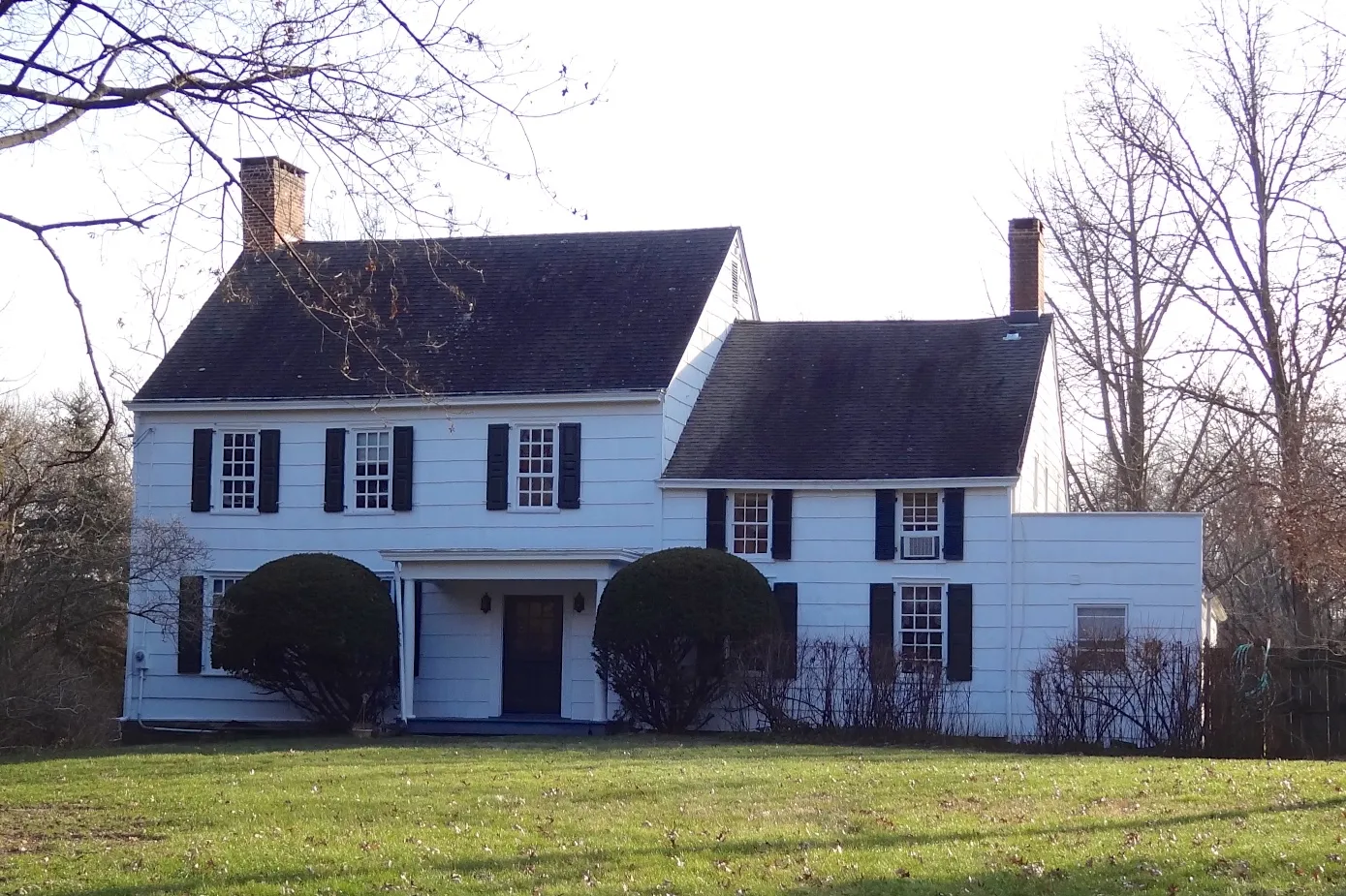 The John Van Doren House in Millstone is a white colonial with dark shutters, two chimneys and a side wing.