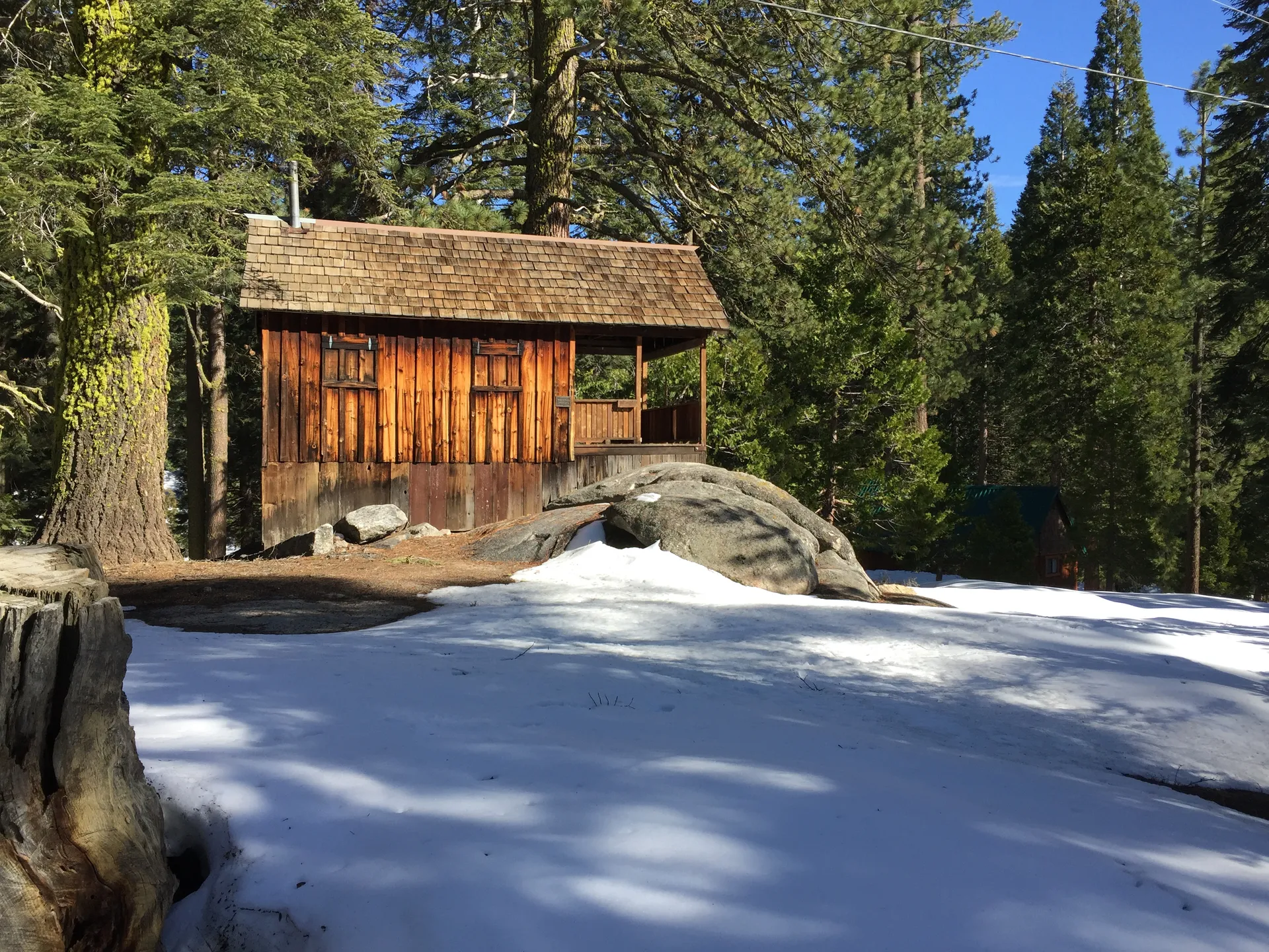 Historic wooden cabin among pines and snow in Wilsonia, California.