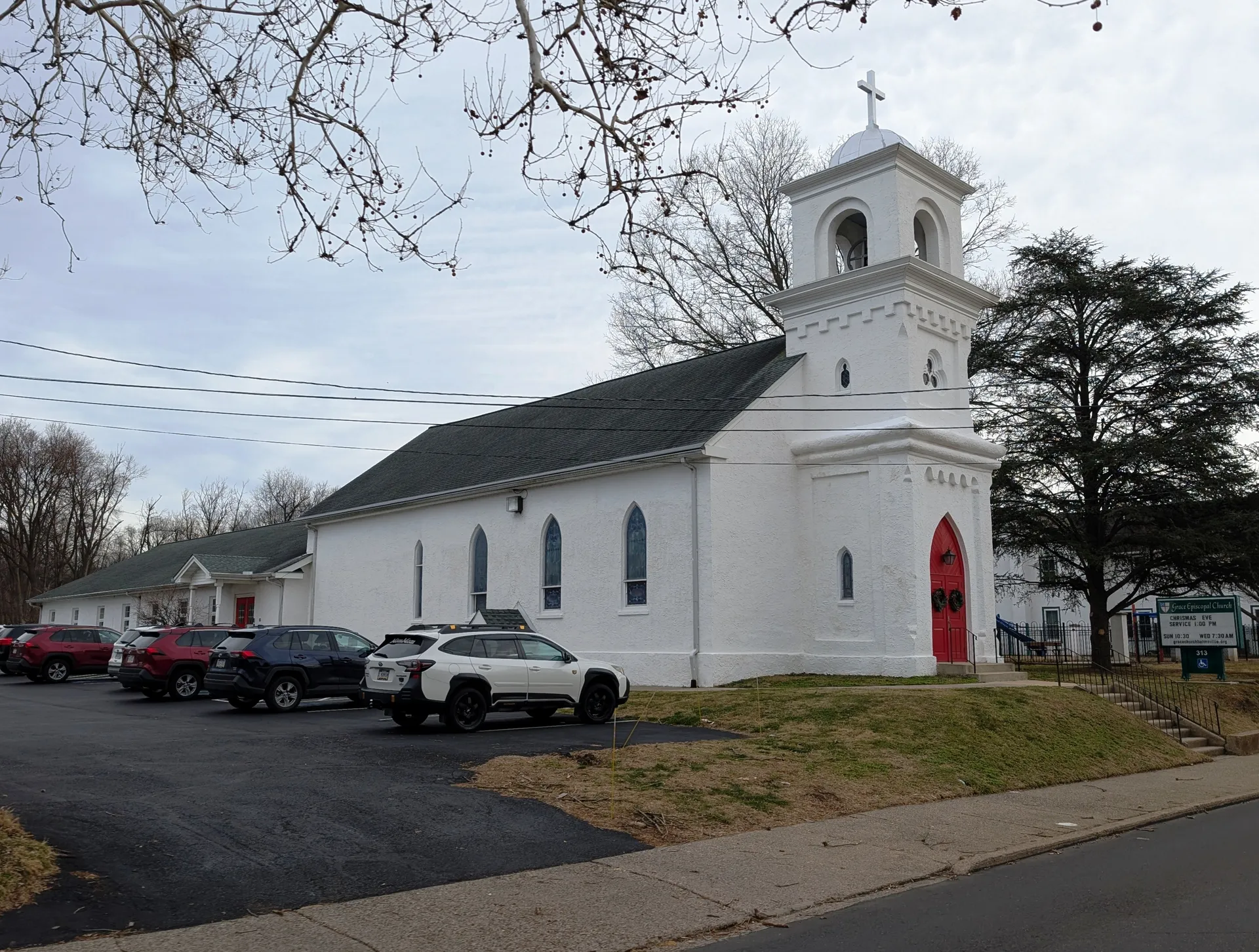Grace Episcopal Church in Hulmeville is a white stucco church with a small bell tower and red door on Main Street.