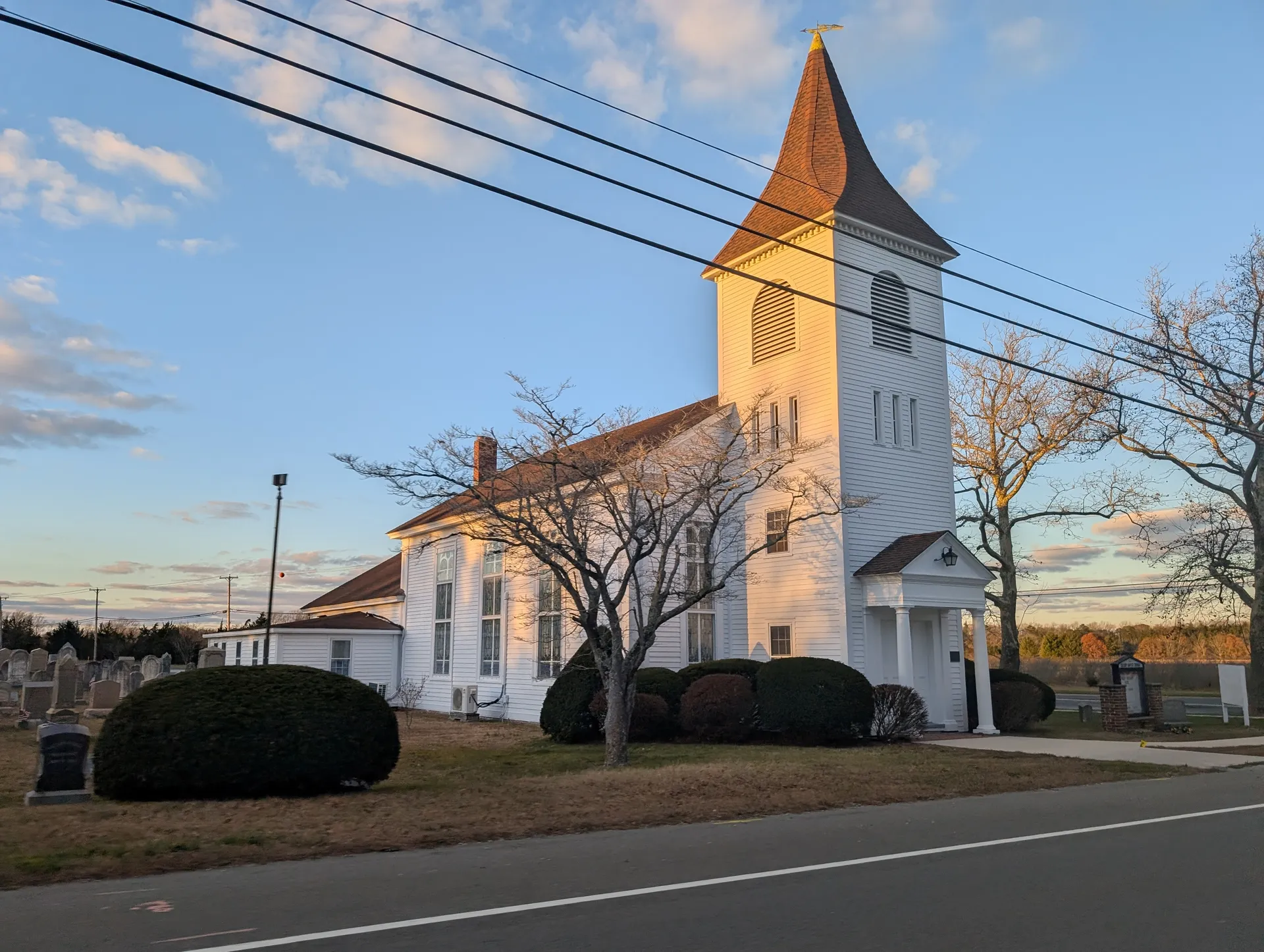 Calvary Baptist Church in Ocean View is a cream church with a tall pointed tower lit by late sun.