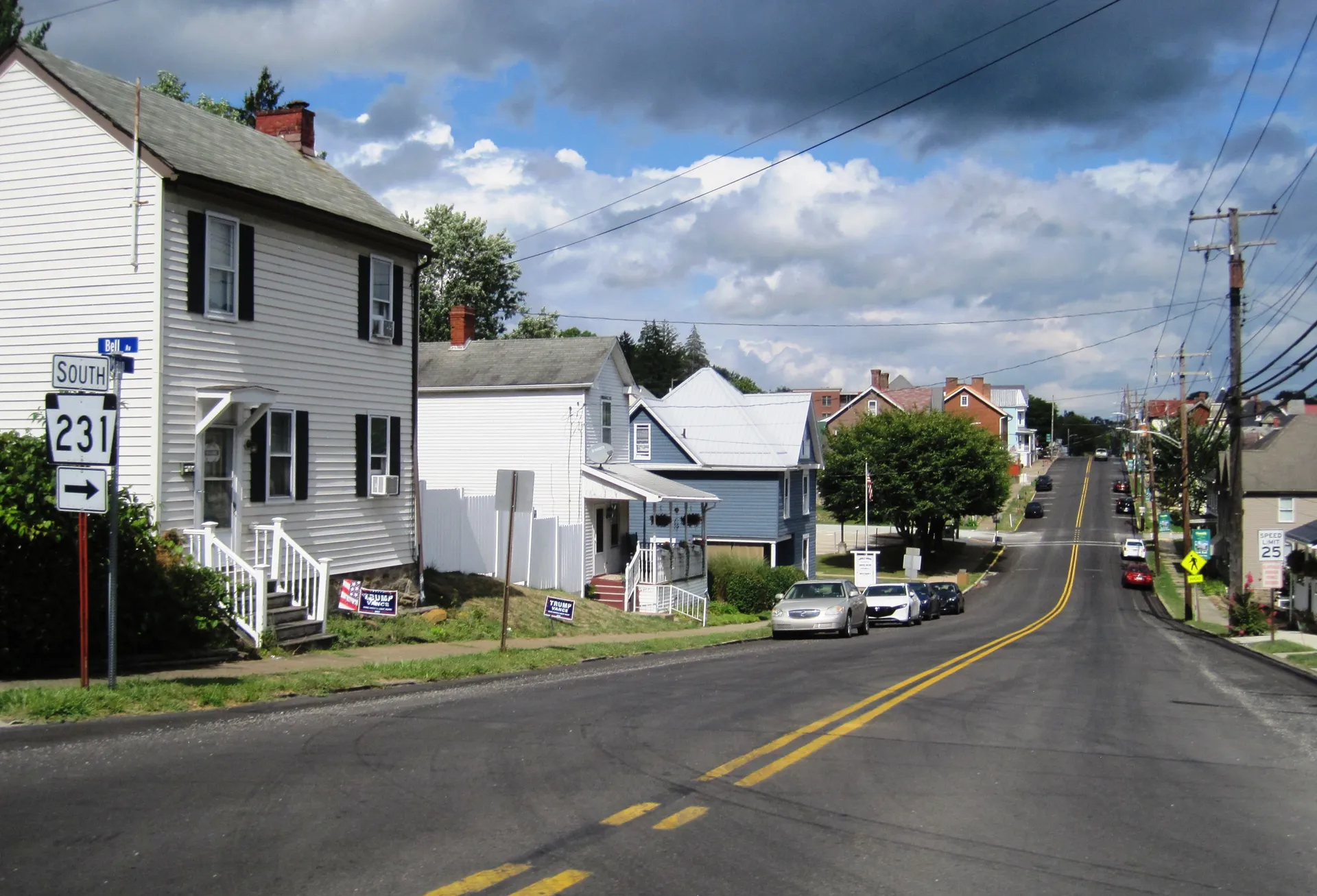 Clapboard houses with porches line the National Road (U.S. 40 and Route 231) through Claysville, with cars parked along the curb.